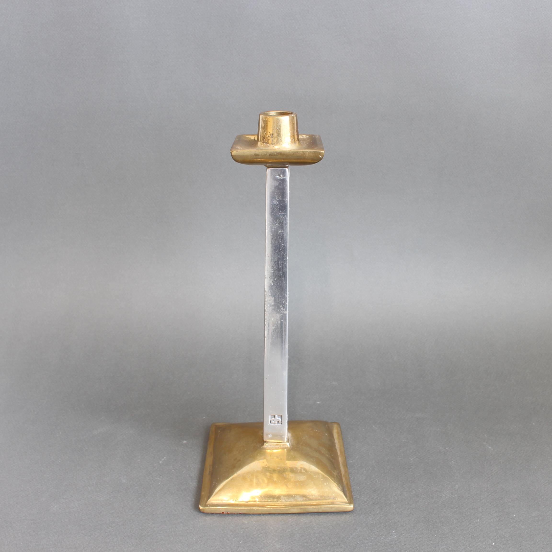 A striking Brutalist candlestick by renowned designer David Marshall, dating to the 1980s. Weighty and tactile, this sculptural piece features a cast aluminium stem bearing the maker’s mark impressed at the base. It rises from a raised square brass