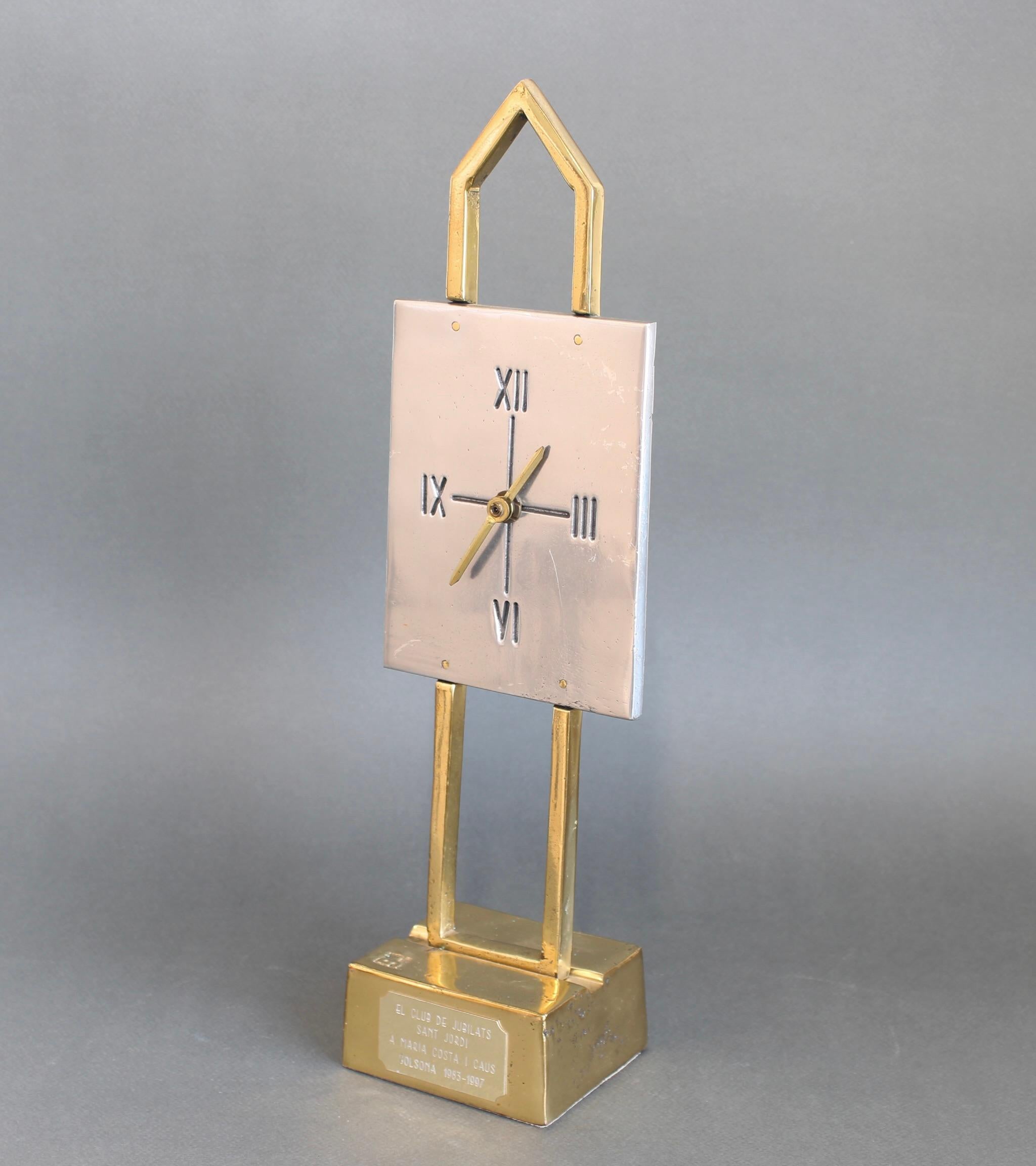 An aluminium and brass table clock by David Marshall (circa 1990s). The piece is very weighty and wonderfully tactile with the maker's mark impressed on the front brass base (which is like a chunky gold bar) supporting the clock. The clock's