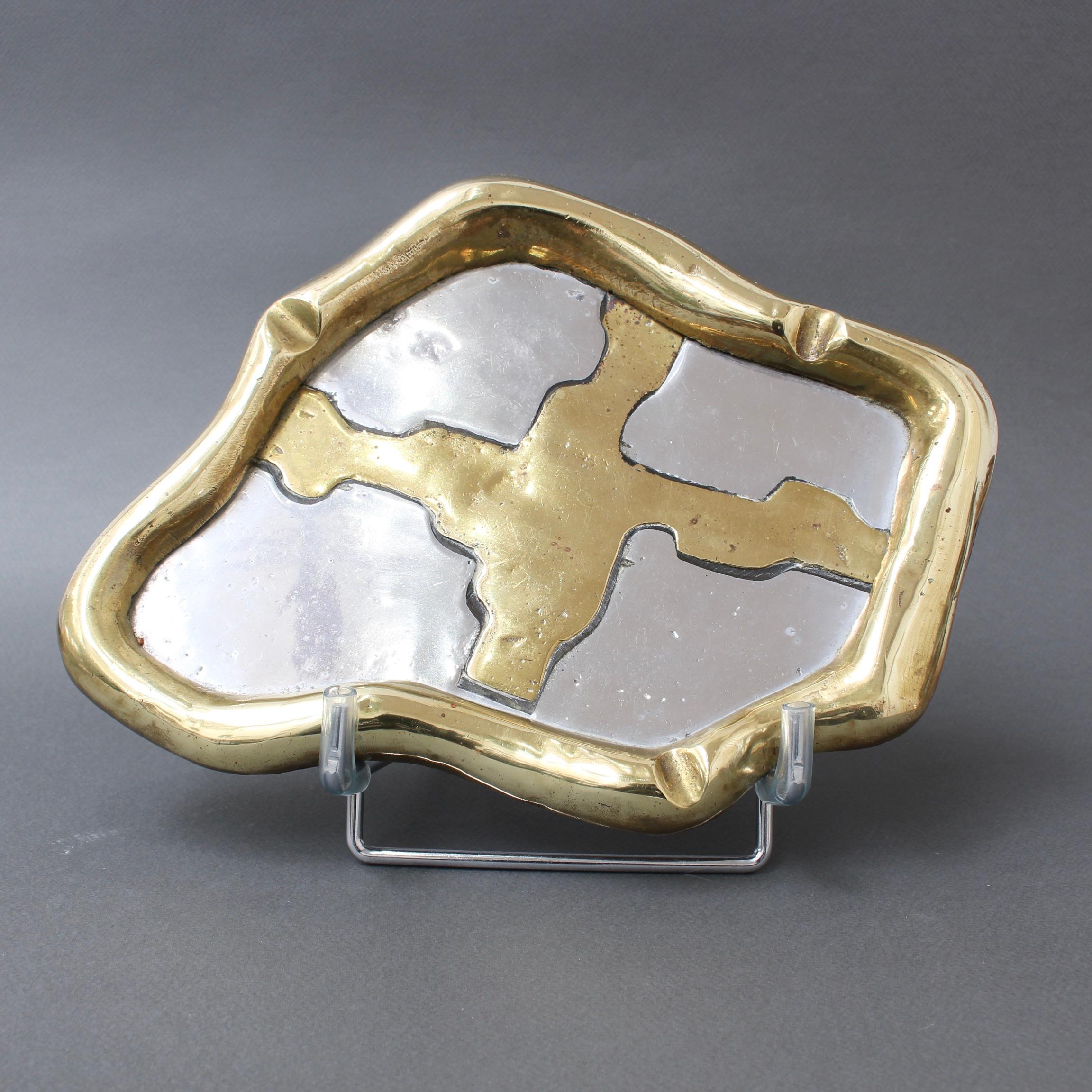 Aluminium and brass vide-poche / ashtray attributed to David Marshall (circa 1980s). This tray is weighty and tactile. The shiny brass middle and edging is stylishly sensuous with curves. This piece is in good vintage condition with characterful
