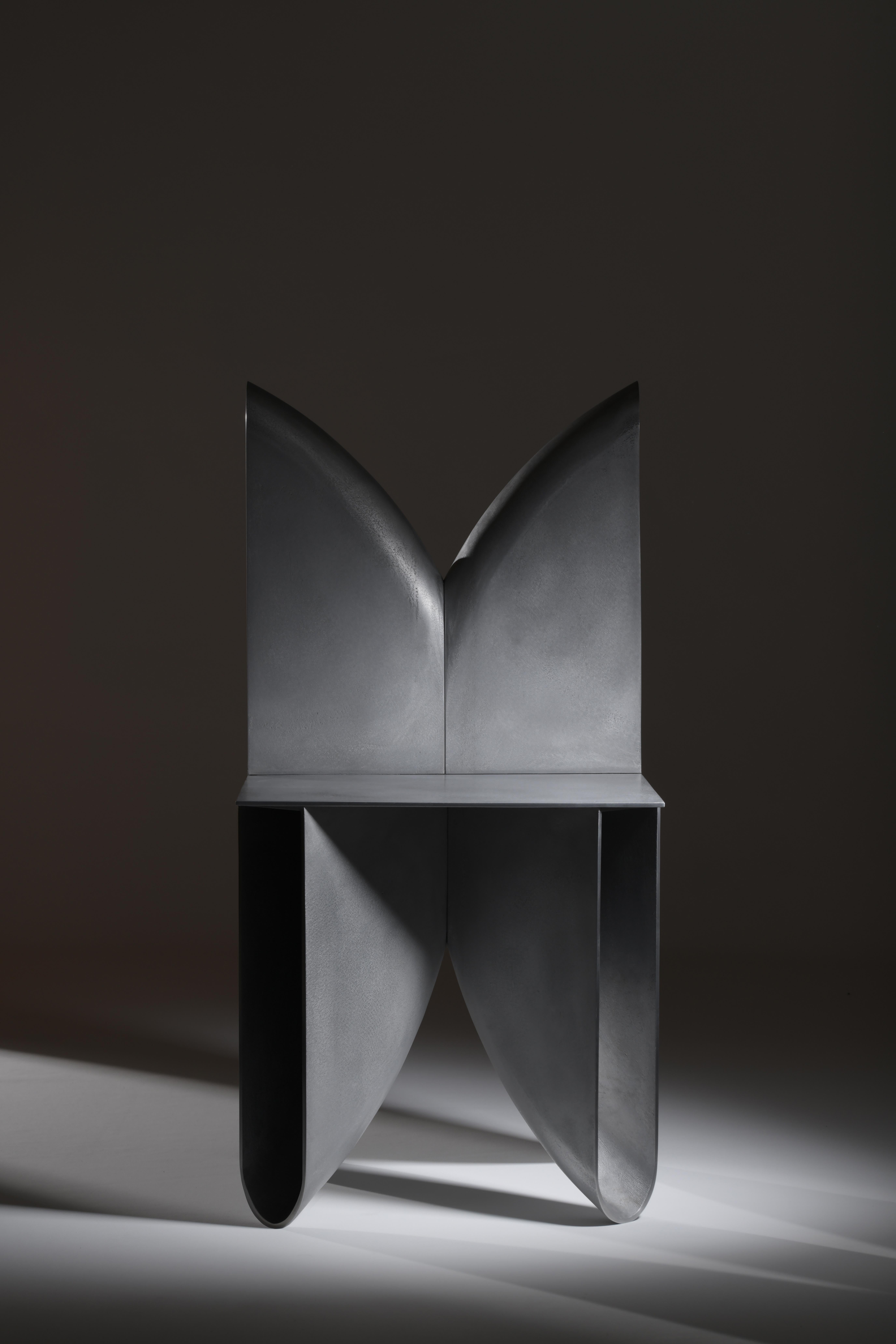A sculptural sand cast metal chair with polished edges.
The chair is composed of 6 sand-cast structural elements; four feet and two backs, that are all produced using the same mould and united by the seat. The metal is finished with restraint,