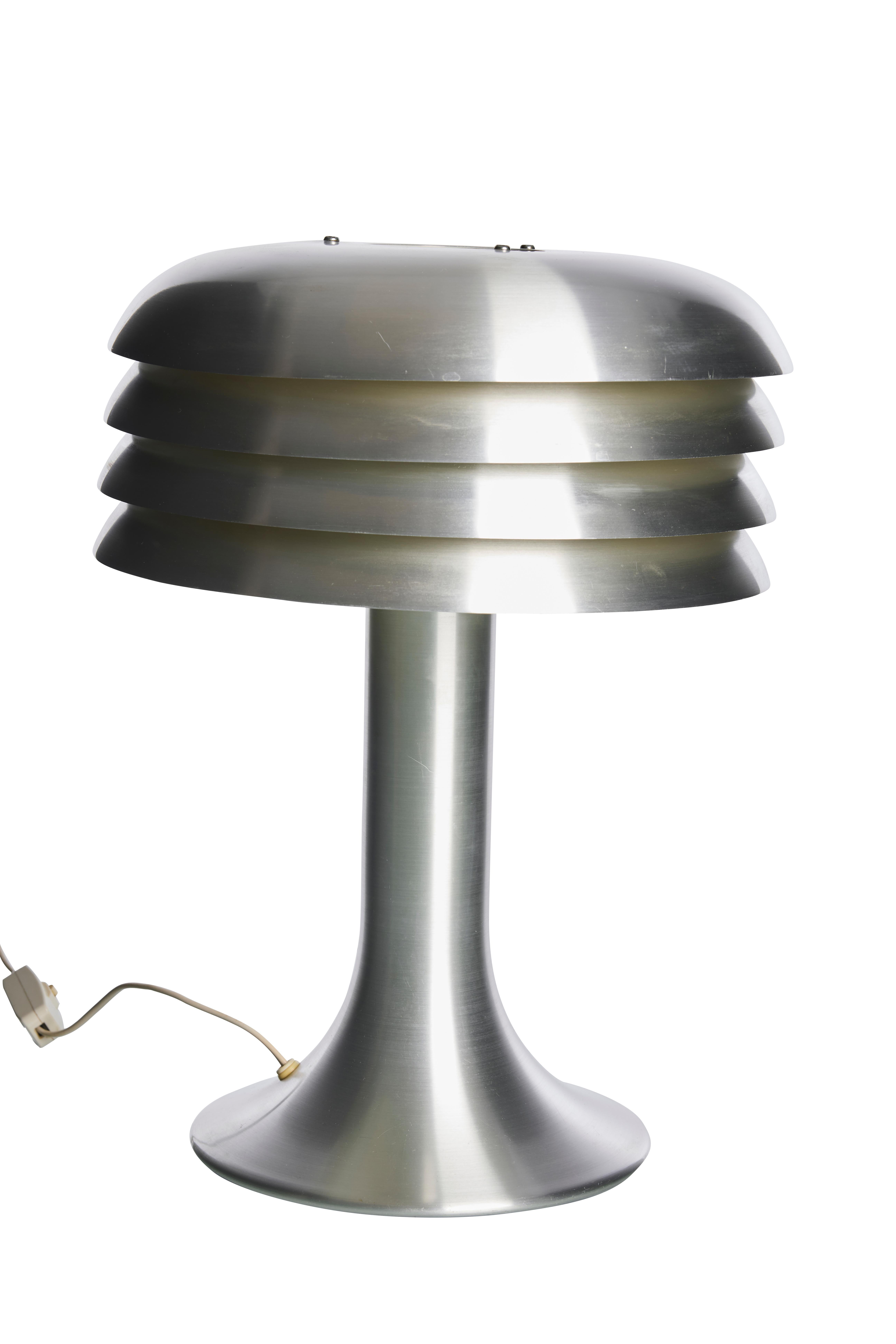 Own a piece of design history with this BN-25 table lamp, an authentic creation by renowned Swedish designer Hans-Agne Jakobsson from the 1960s. This lamp is a true testament to mid-century Scandinavian craftsmanship, featuring a sleek brushed
