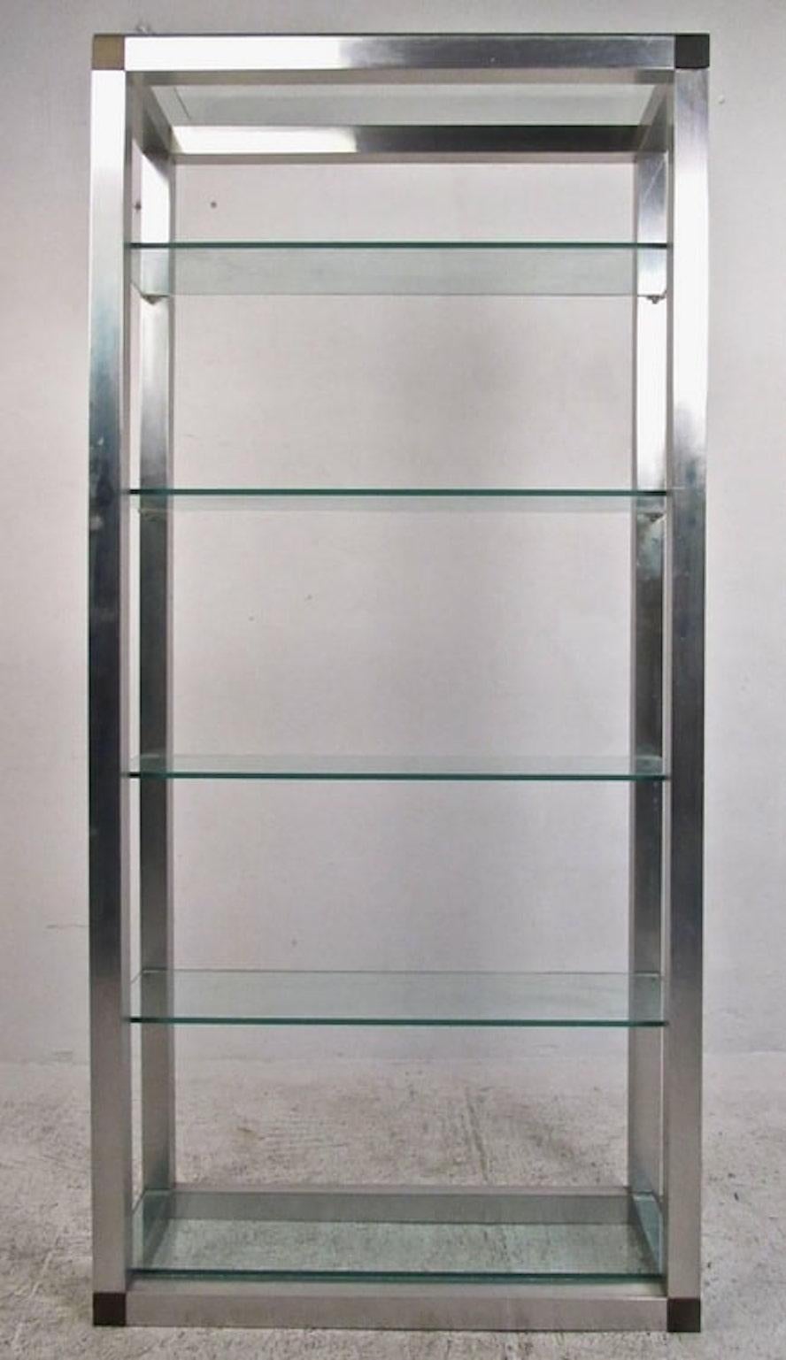 This vintage display unit makes an ideal storage shelving system for a variety of interiors. Aluminum finish with corner trim is outfitted with thick glass shelves. 
Please confirm item location (NY or NJ).