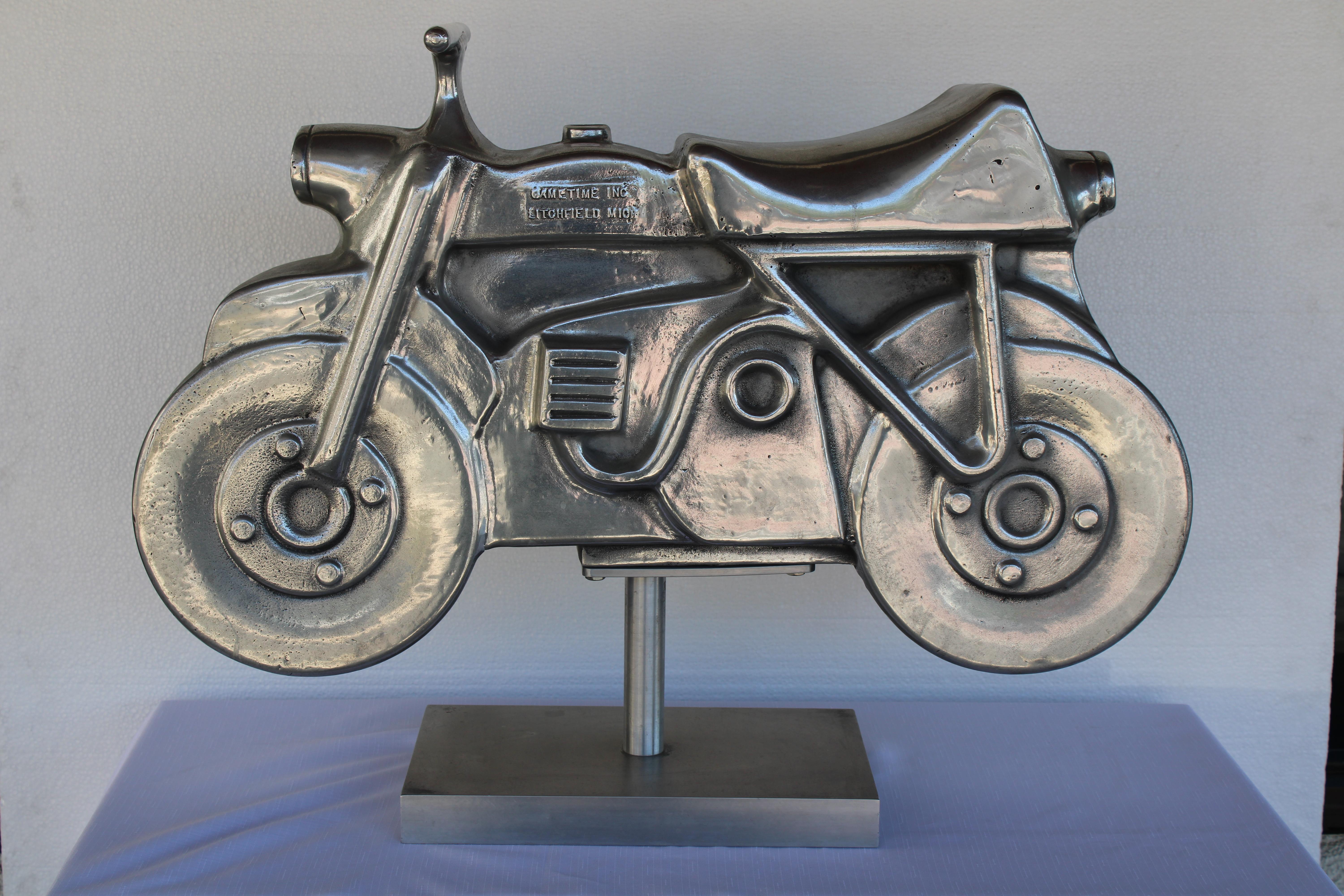 This aluminum motorcycle sculpture was originally a playground spring ride located throughout parks. Spring is not included. Motorcycle has been high polished and put on an aluminum stand.  It's more sculptural and part of Americana history. 