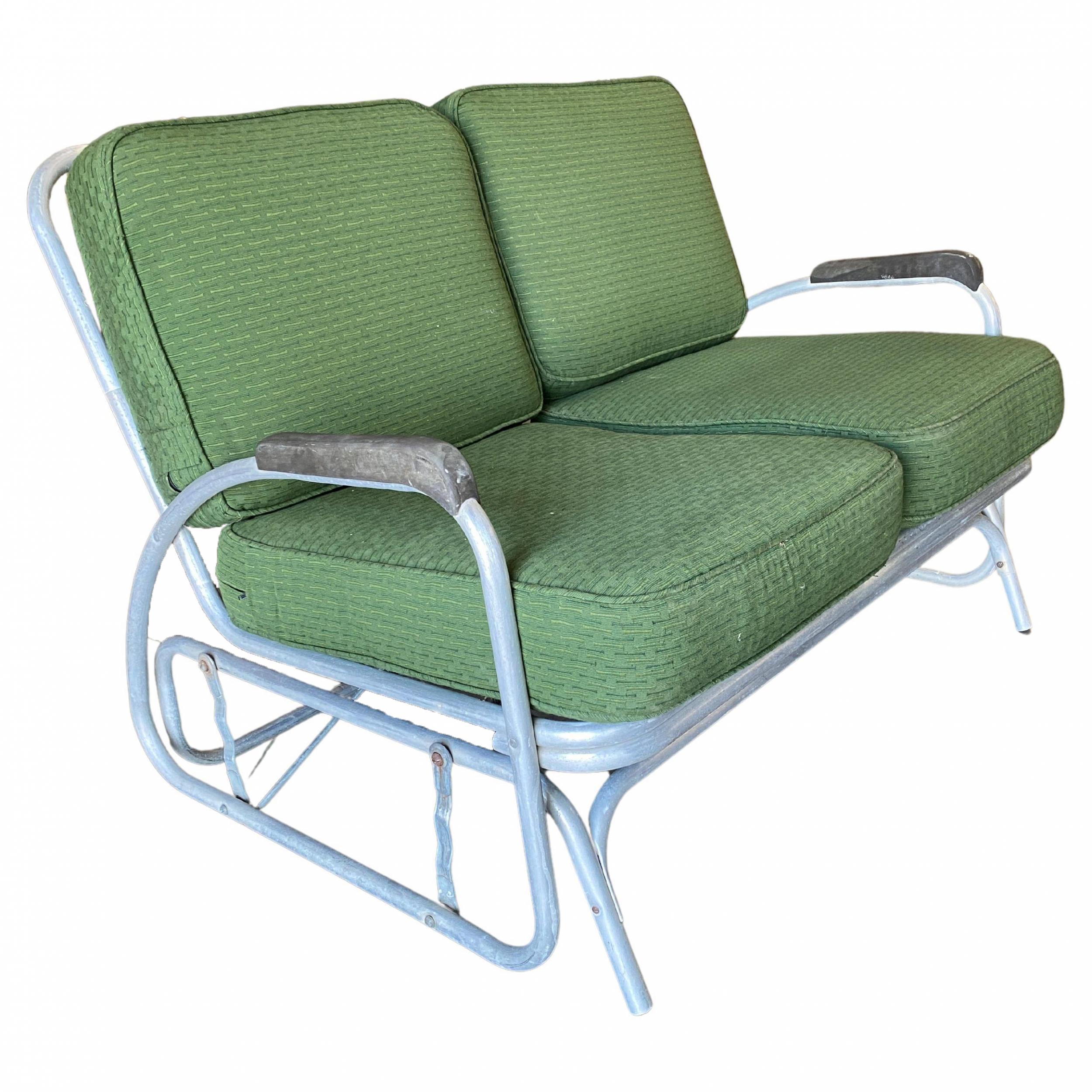 Art Deco Terrassen-Sessel Paar und Loveseat Set bestehend aus einem Aluminiumrahmen mit dekorativen Streamline Geschwindigkeit Arme. Sowohl die Stühle als auch der Sessel ruhen auf einem Gleitfuß, der sie hin und her schaukeln lässt.