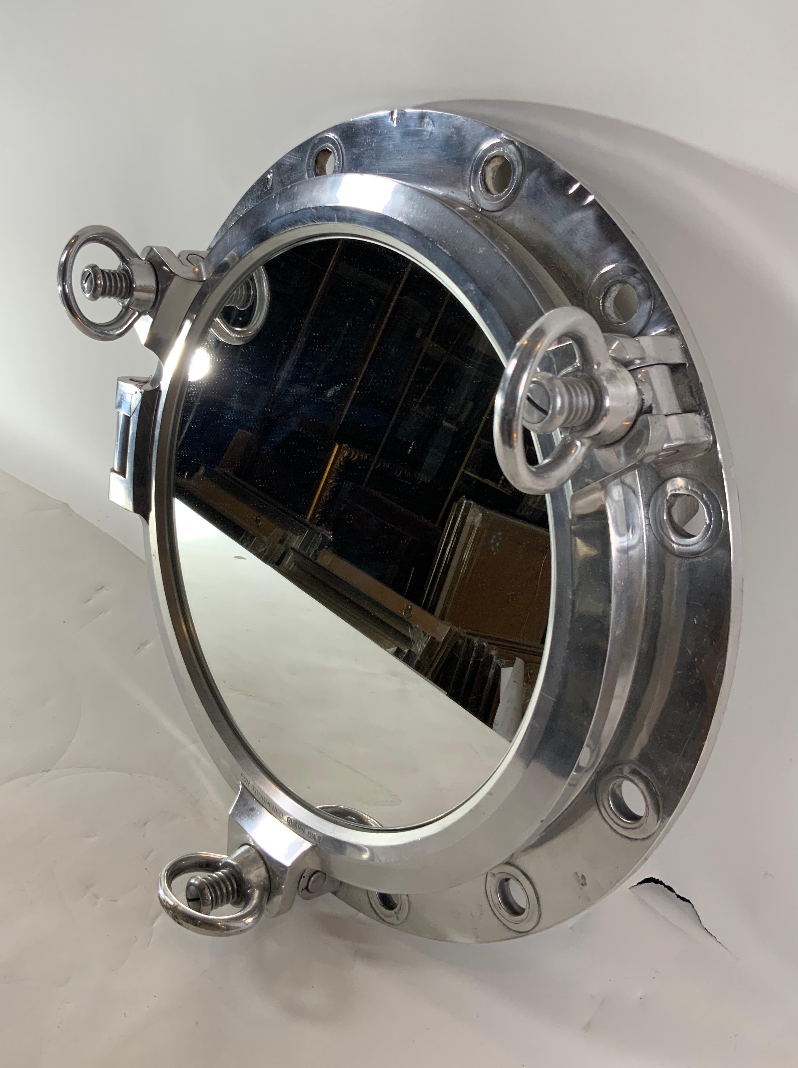 Authentic polished aluminum ship's porthole fitted with a glass window. Door is hinged and fitted with three dogbolts. The highly polished porthole is ready for display.

Overall dimensions: mirror diameter: 14
