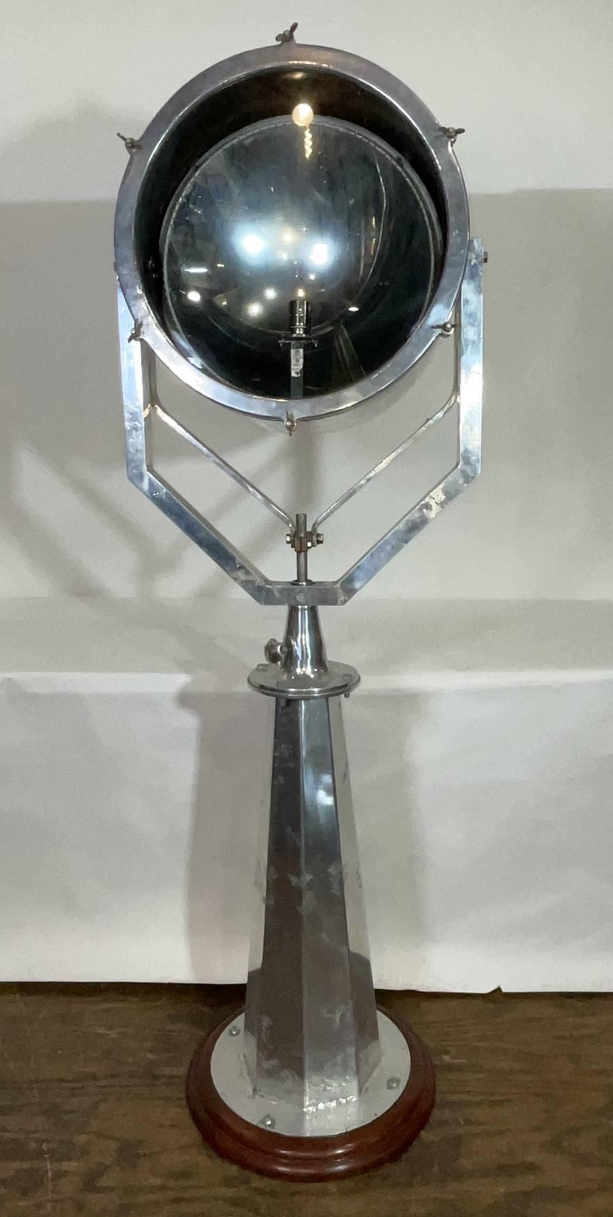 Projecteur de bateau en aluminium poli avec vitellus incliné monté sur un socle. Le projecteur pivote à 360 degrés, de haut en bas. La base personnalisée est montée sur une épaisse plinthe en bois avec une finition vernie. Relique nautique très