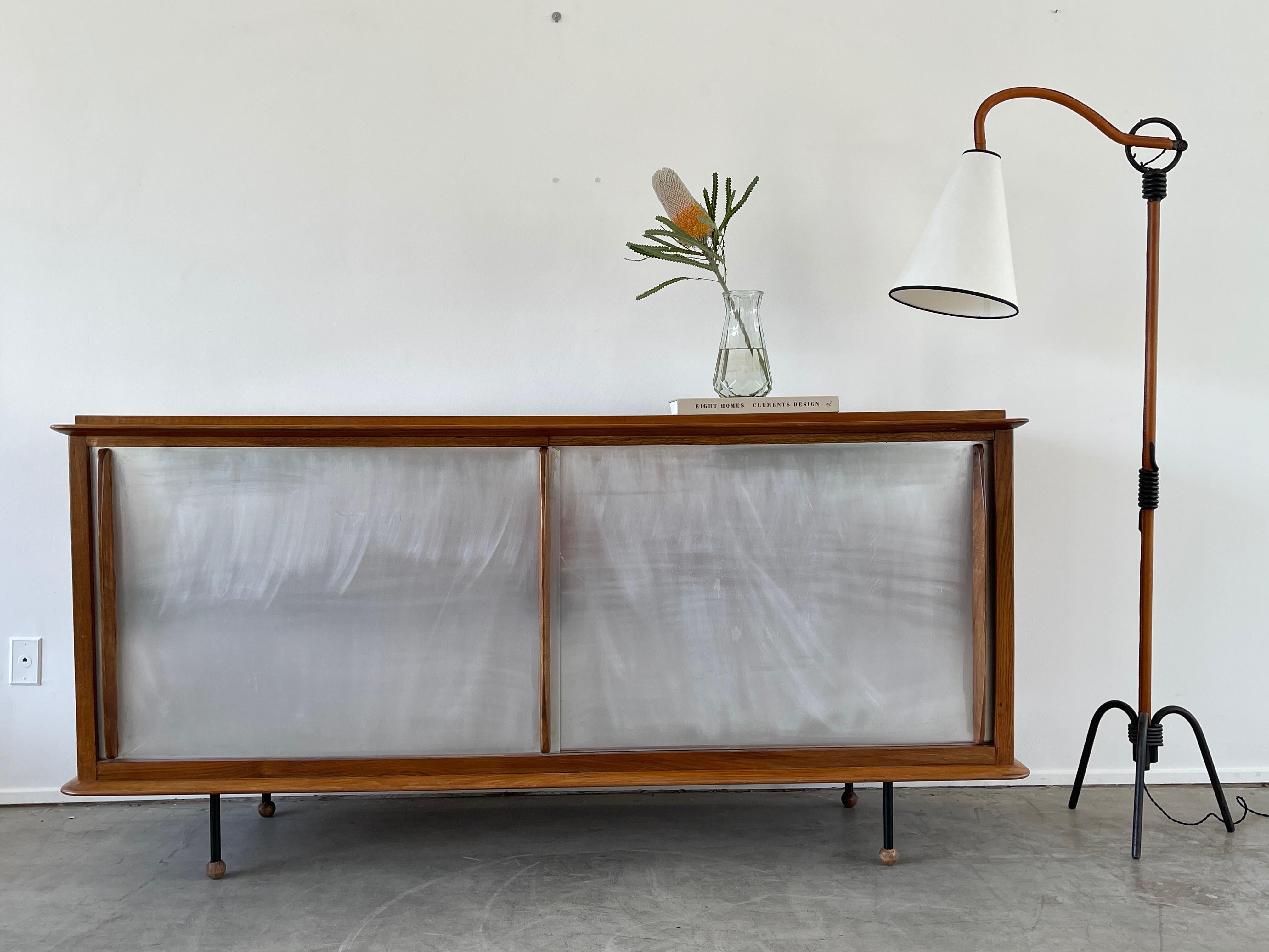 Unique sideboard with wonderful lines originating from Switzerland, circa 1950's
In similar style to Jean Prouve 
Aluminum sliding doors with wood handles and wood feet. 
Incredible piece.