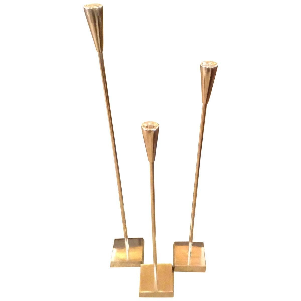 Modern and elegant, this trio of tall, slender candle sticks will be the perfect touch beside a master bathtub or gathered on a fireplace hearth. Fashioned from aluminum, of varying heights, the polished silver finish gives them an extra dose of