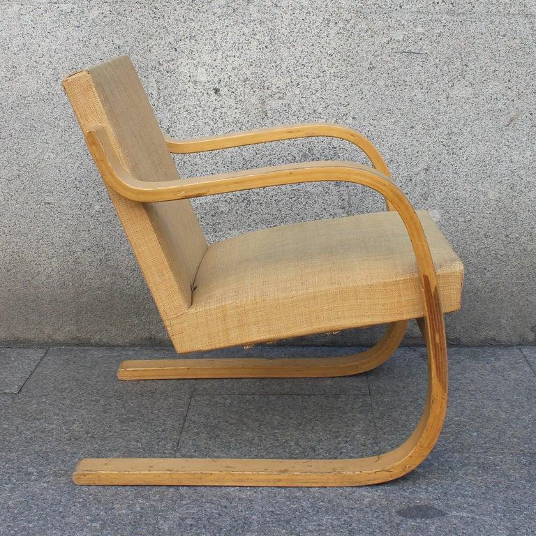 Armchair designed by Alvar Aalto manufactured, circa 1960.

Curved birch plywood and braided vegetable fiber. 
Measures: 74 x 61 x 69 cm

In good original condition with minor wear consistent with age and use, preserving a beautiful
