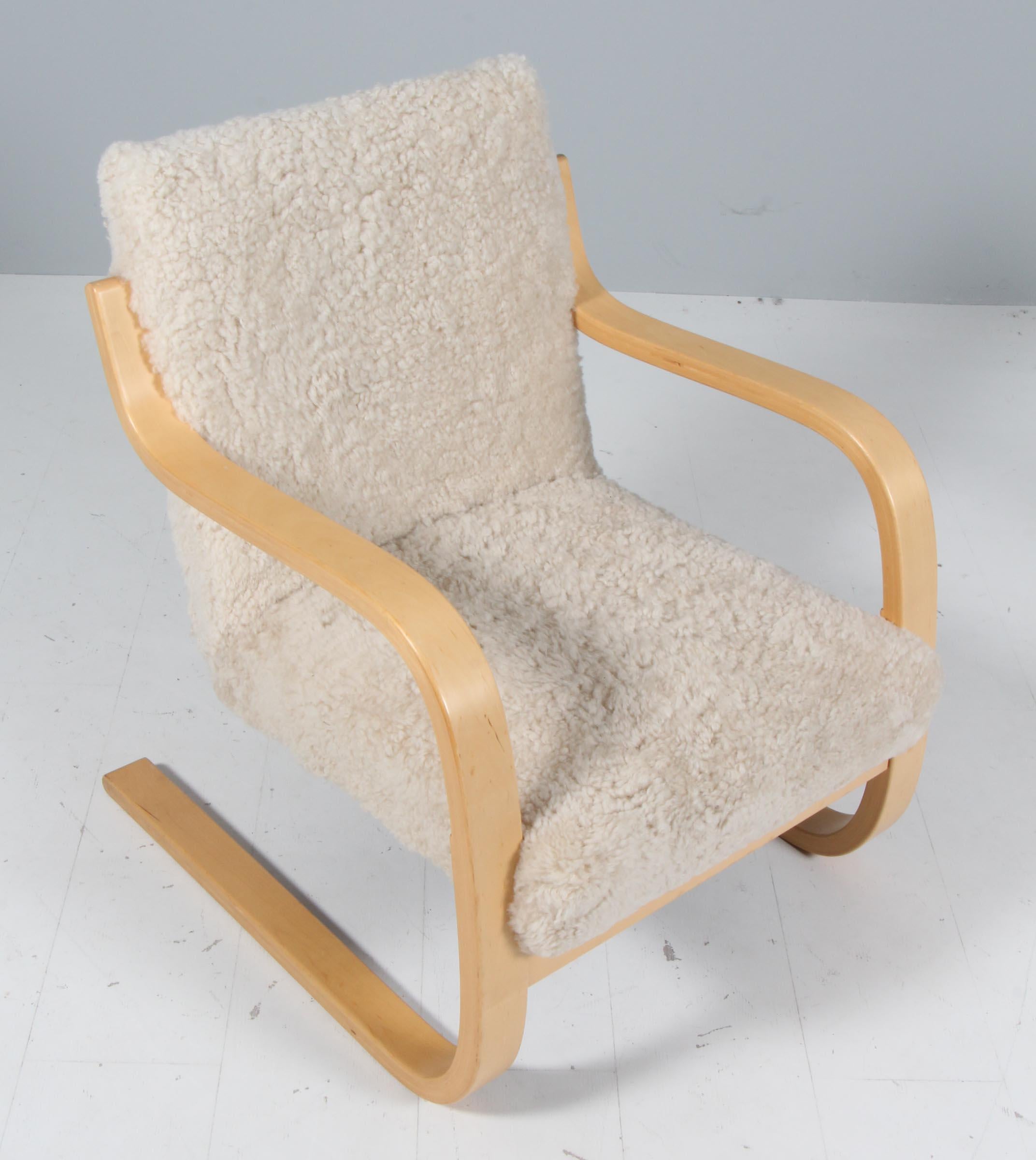 Loungesessel, entworfen von Alvar Aalto, hergestellt um 1960.

Neu gepolstert mit Lammfell

Gebogenes Birkensperrholz und geflochtene Pflanzenfasern. 
Maße: 74 x 61 x 69 cm.
 