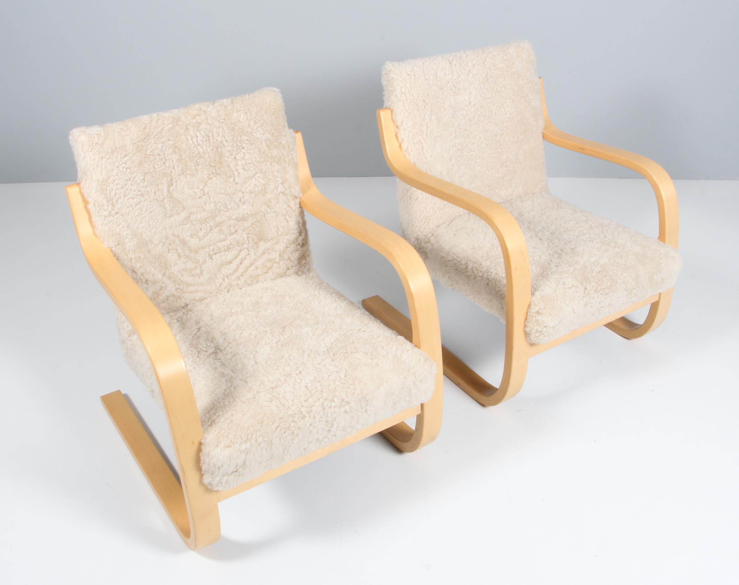 Lounge chairs designed by Alvar Aalto manufactured, circa 1960.

New upholstered with lambskin

Curved birch plywood and braided vegetable fiber. 
Measures: 74 x 61 x 69 cm.
 