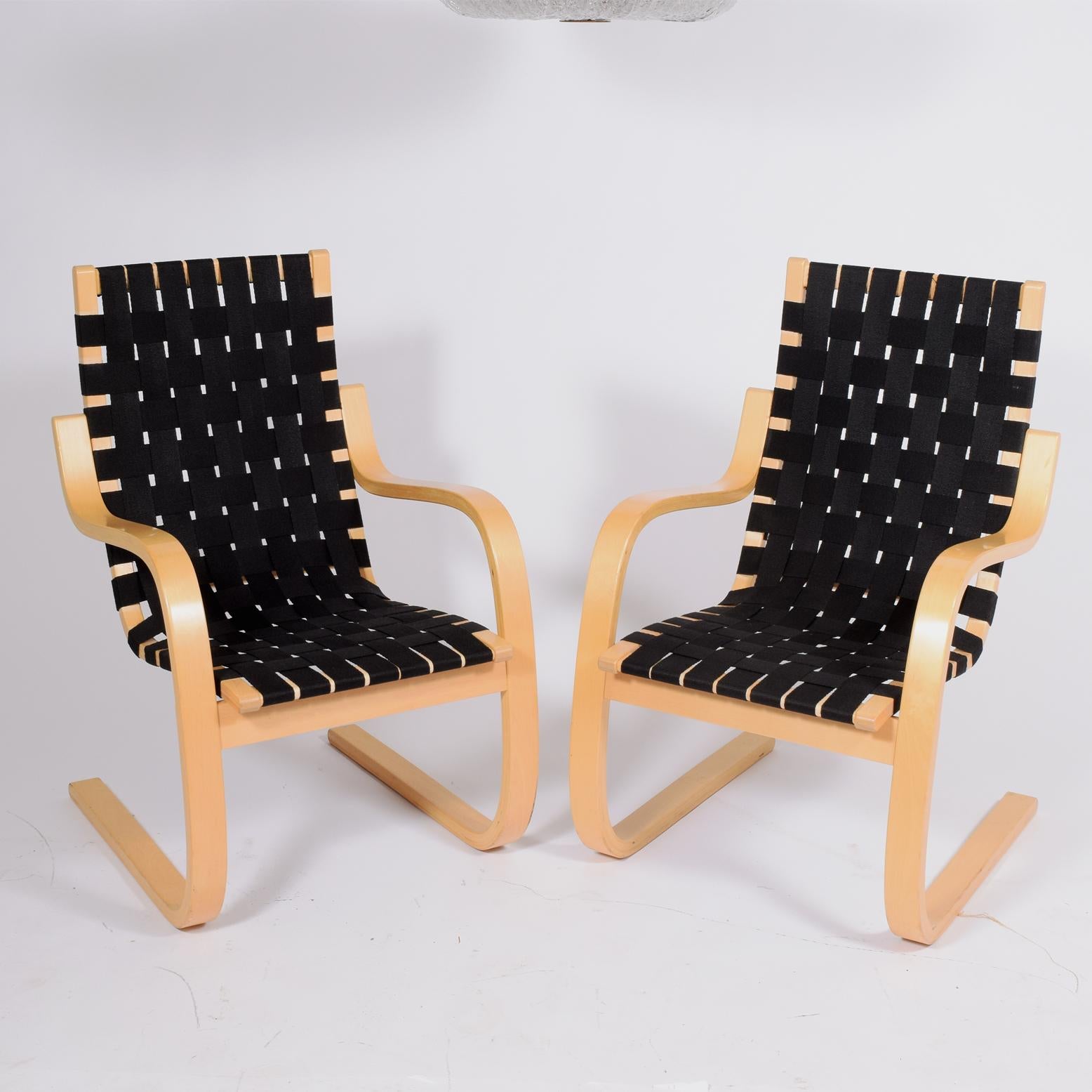 Alvar Aalto model 406 lounge chairs. Bent natural wood frames with woven canvas strapped seating. In original condition with some fading paper label