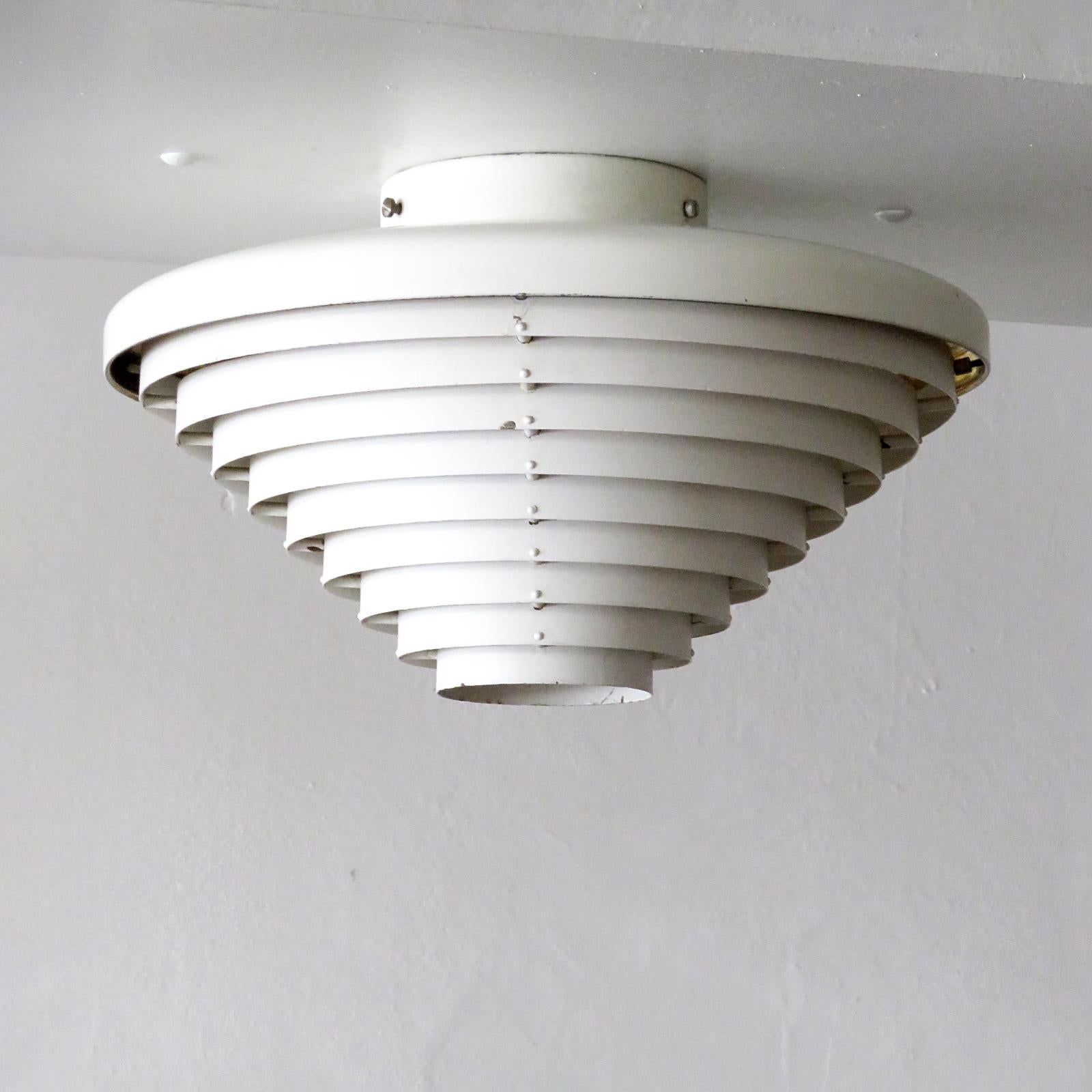 Wonderful model 'A205' ceiling lamp by Alvar Aalto, originally designed for the National Pensions building in Helsinki, made of louvered, white lacquered steel rings under a brass 'roof', early example by original manufacture Valaistustyö Ky,