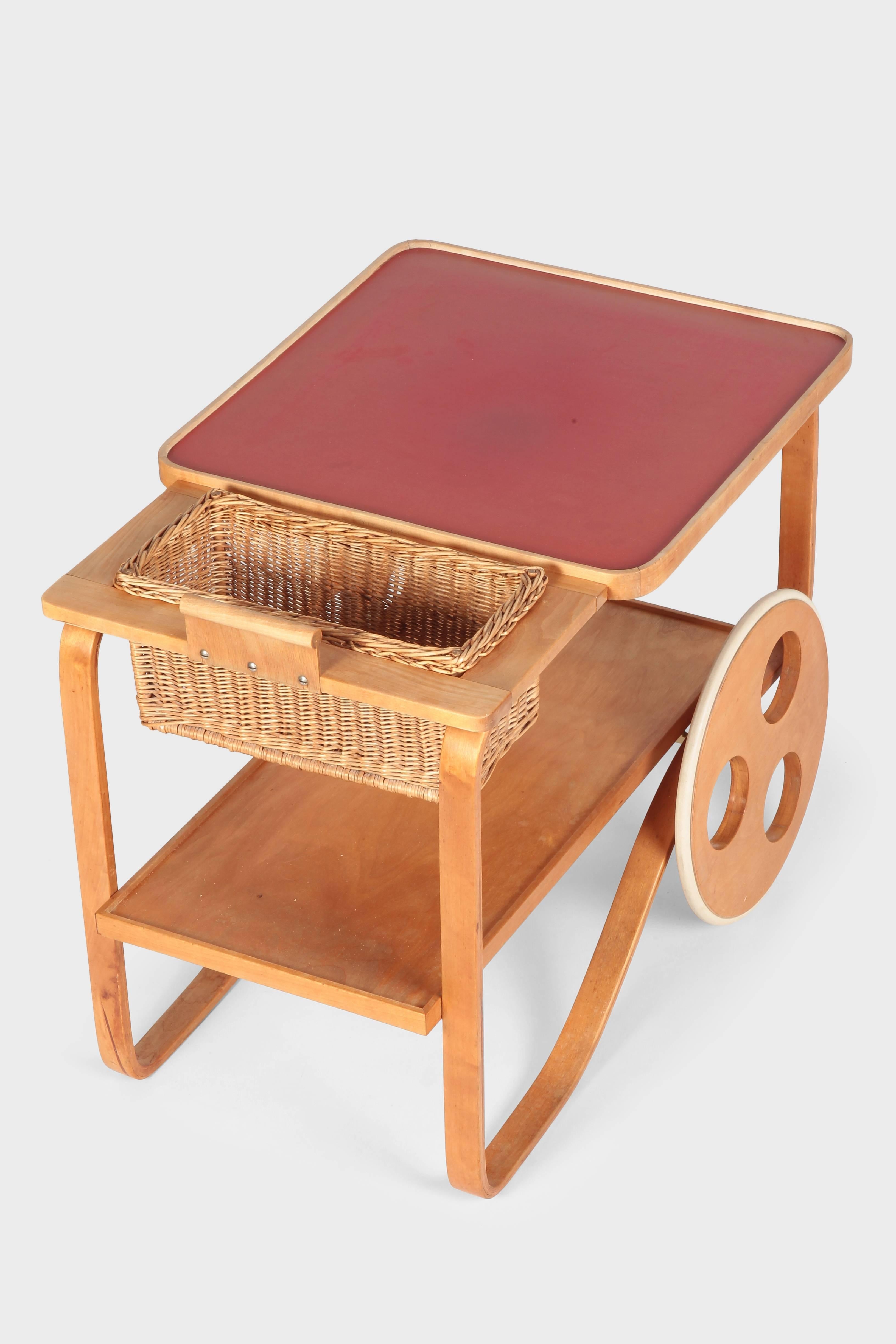 Alvar Aalto bar cart designed for Wohnbedarf in 1937. Very rare object. Molded plywood and solid birchwood, completed with a resistant, red linoleum surface and a unattached wicker basket. Gently restored, in very good condition.