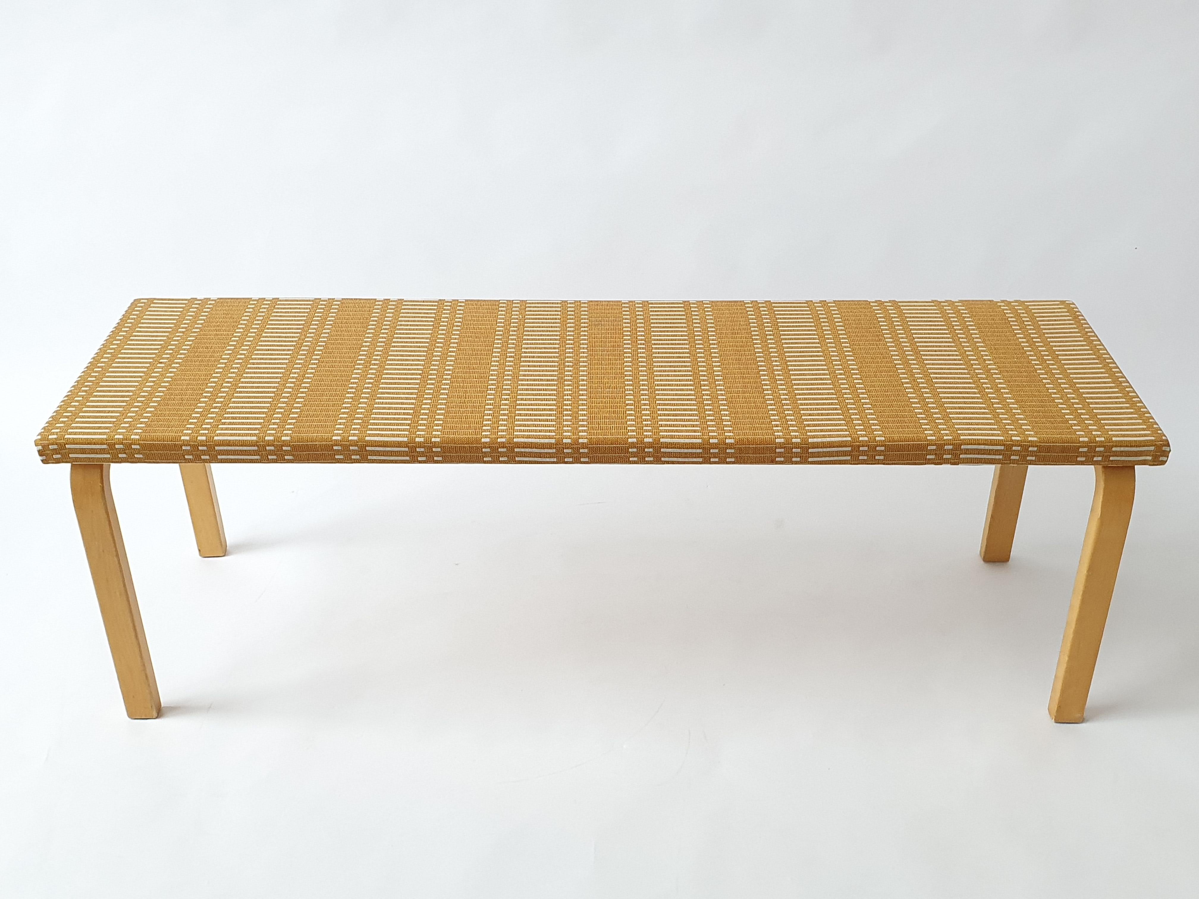 Banc Artek, designer Alvar Aalto. Le banc a récemment été retapissé avec le tissu Helios Ochre de Johanna Gullichsen. Le banc est en bon état d'usage.