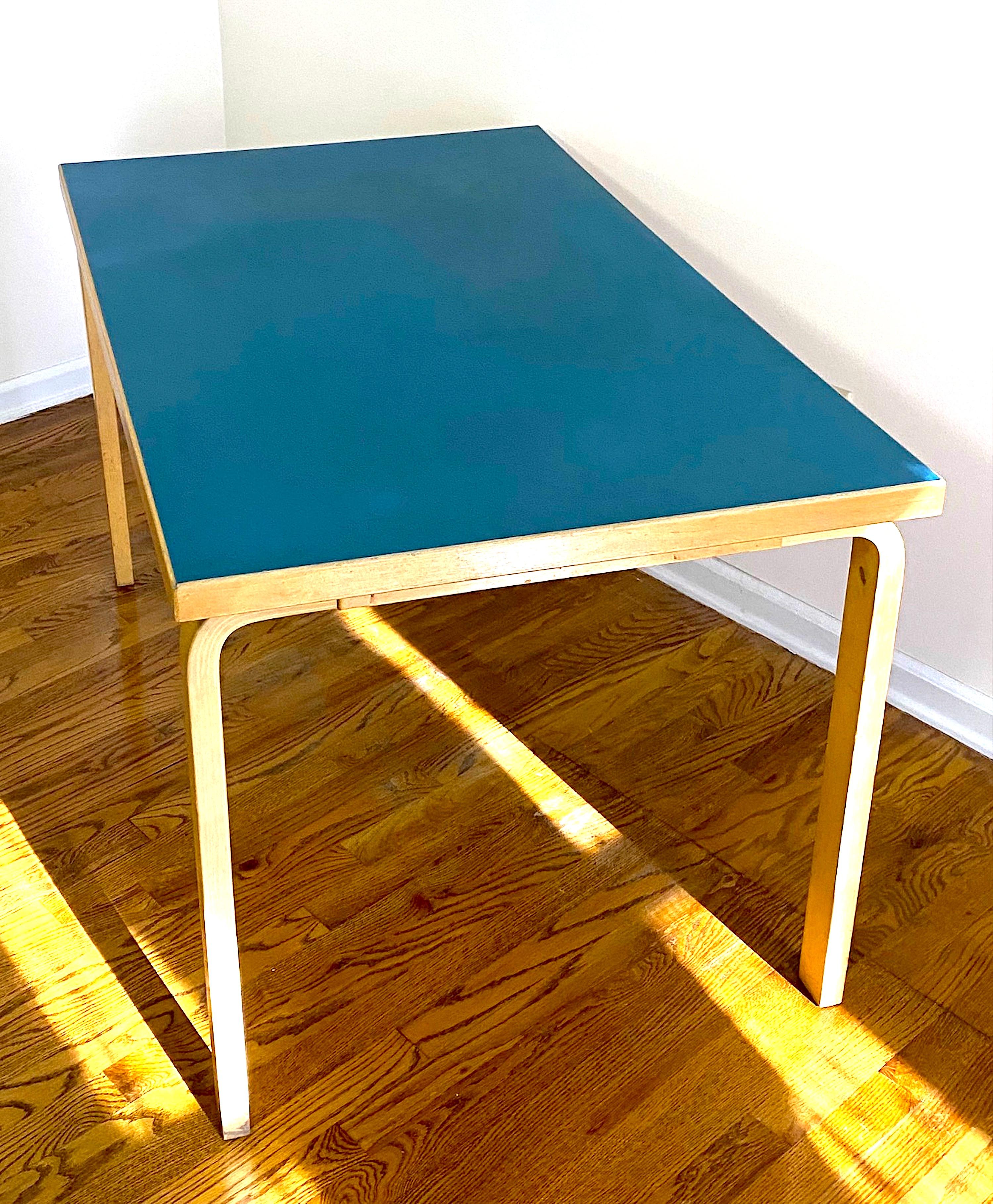 A fine example of bauhaus design by Finnish designer Alvar Aalto, this birch bent leg table has the original and no longer available blue linoleum top dating it to the later 1950s. It is bent Birch wood with a blue linoleum top and measures 48