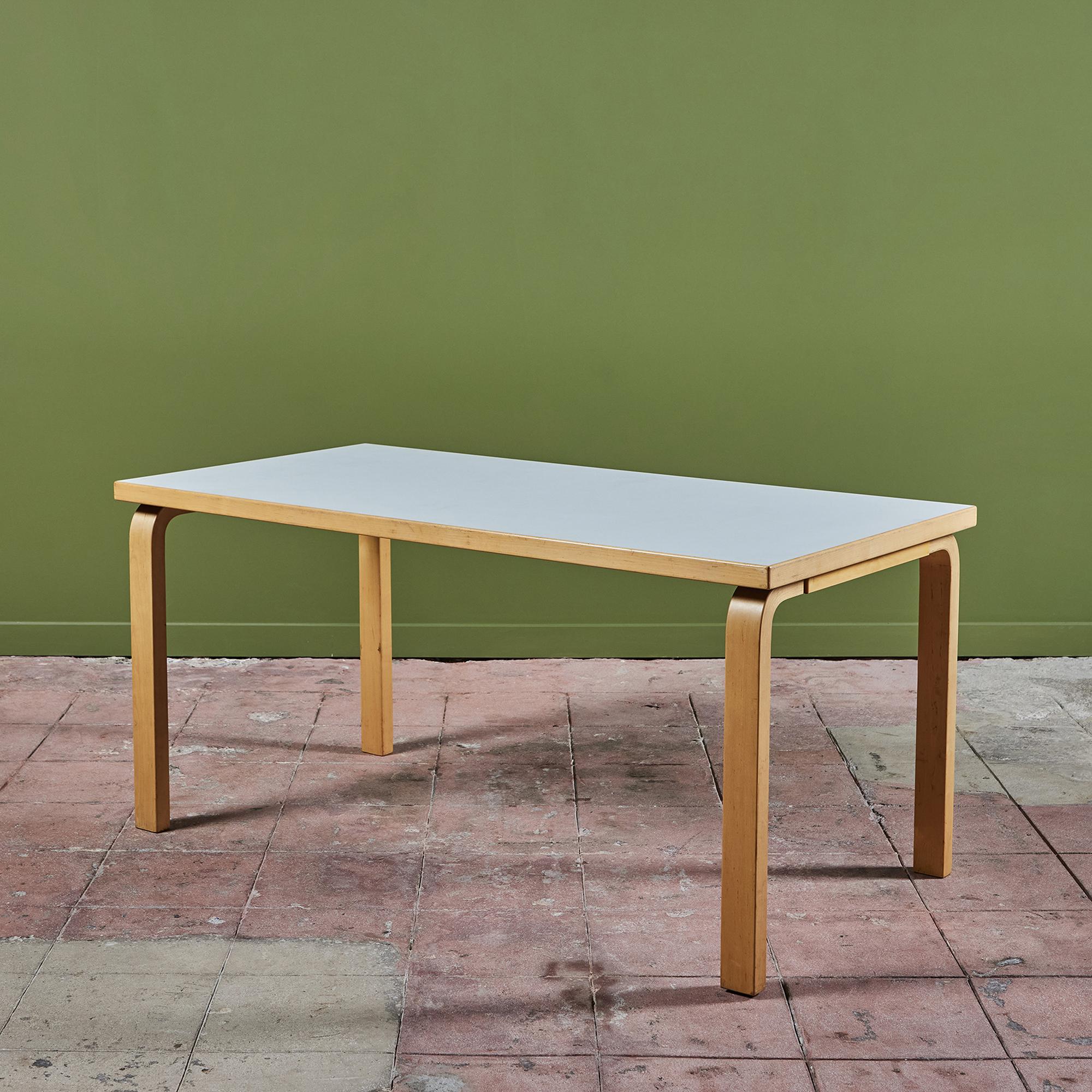 Dining table by Alvar Aalto, c.1980s. The table features a rectangular laminate top that sits atop bent birch wood legs. This design features Aalto’s signature method of joining table tops to table legs, by mounting with screws from