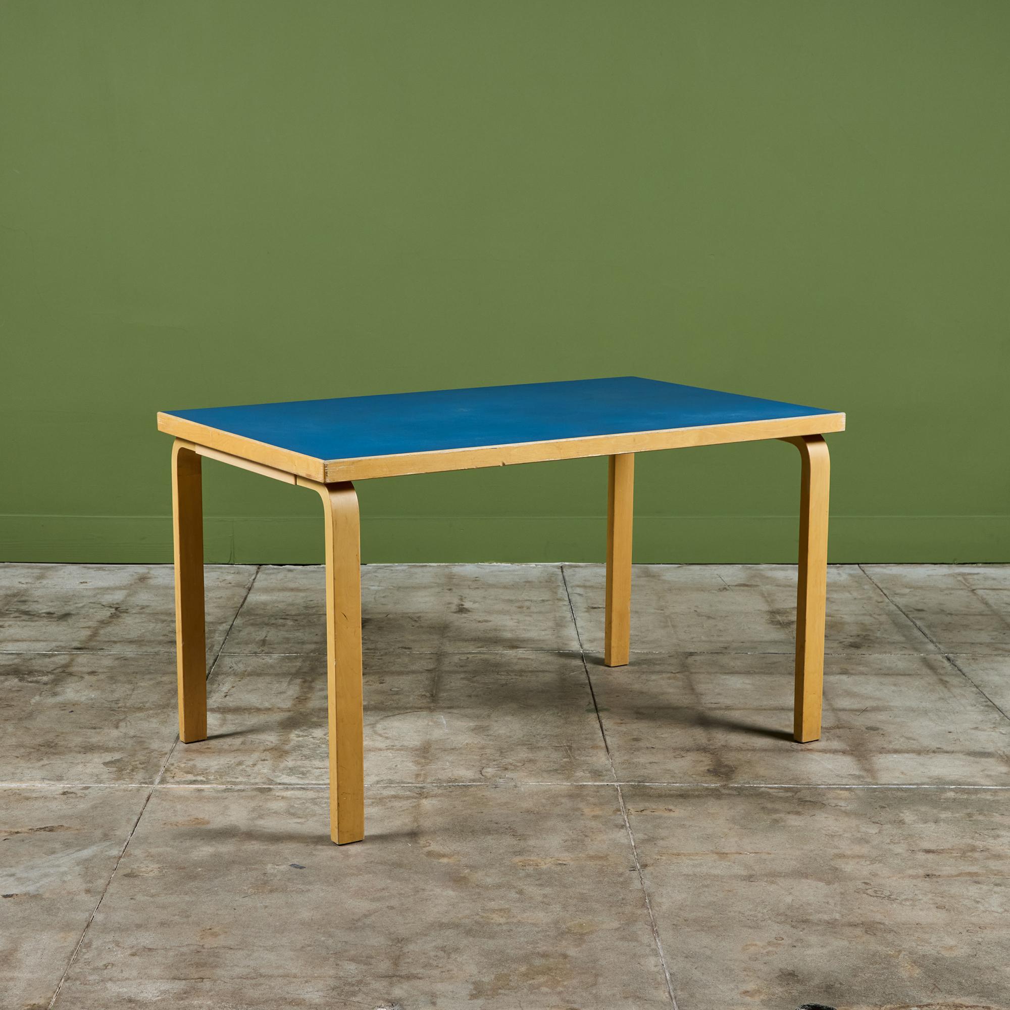 Dining table designed by Alvar Aalto, for Artek.  The table features a rectangular blue laminate top that sits atop bent birch wood legs. This design features Aalto’s signature method of joining table tops to table legs, by mounting with screws from
