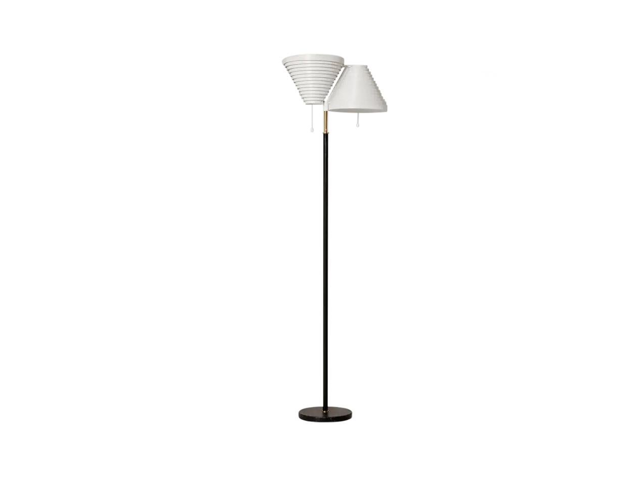 A brass floor lamps, stem and base covered with black leather. White lacquered metal shades. Manufactured and marked by Valaisinpaja Oy.
Pair available.

This popular floor light features two hand-riveted shades, each formed from delicate, lacquered