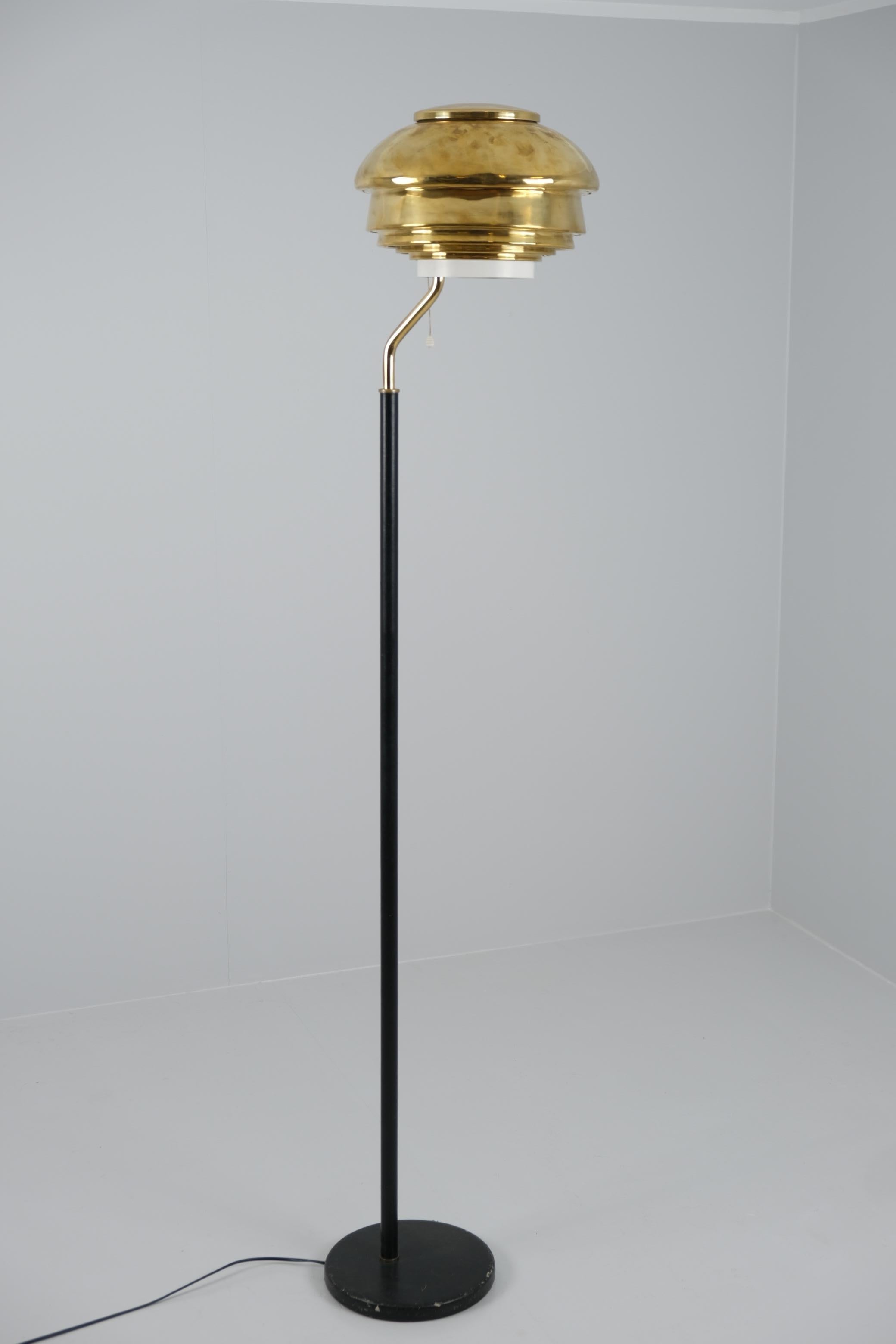 Lampadaire modèle A808 conçu par Alvar Aalto et fabriqué par Valaistustyö en Finlande à la fin des années 50 et au début des années 60. La lampe a un air de science-fiction futuriste, la lumière traversant l'abat-jour en laiton fendu en un