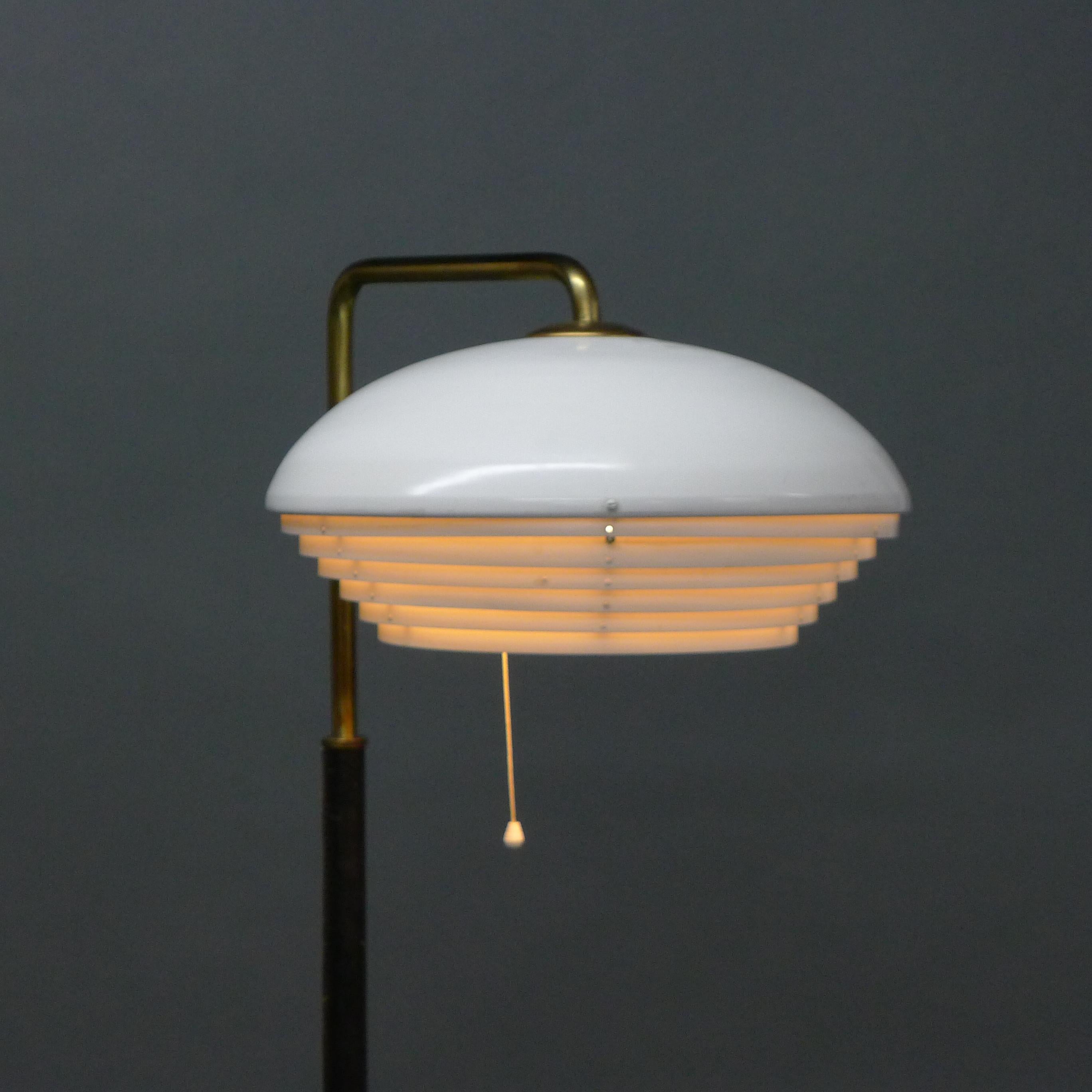 Alvar Aalto model A811 floor lamp, produced by Valaistustyö, Finland 1950s.

This original floor lamp has a white painted metal louvred shade on a brass neck extending into a leather covered pole and base.  It has a pull cord to extending from the