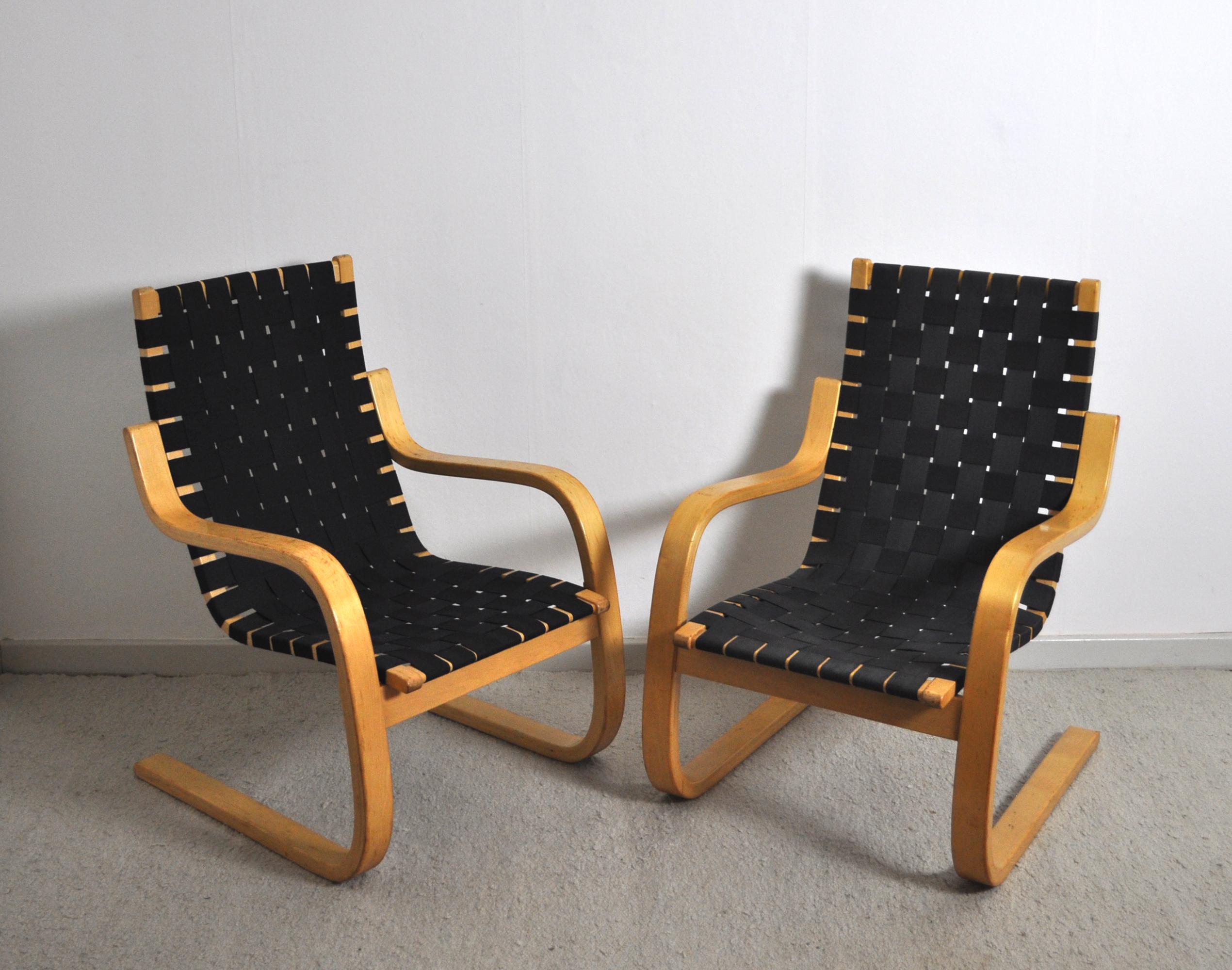 Cantilevered lounge chairs model 406 designed by Alvar Aalto for Artek. Bent laminated birch wood frames with woven canvas strapped seating. In original condition with some fading to the strapping and wear to the frame. 
Good vintage condition with