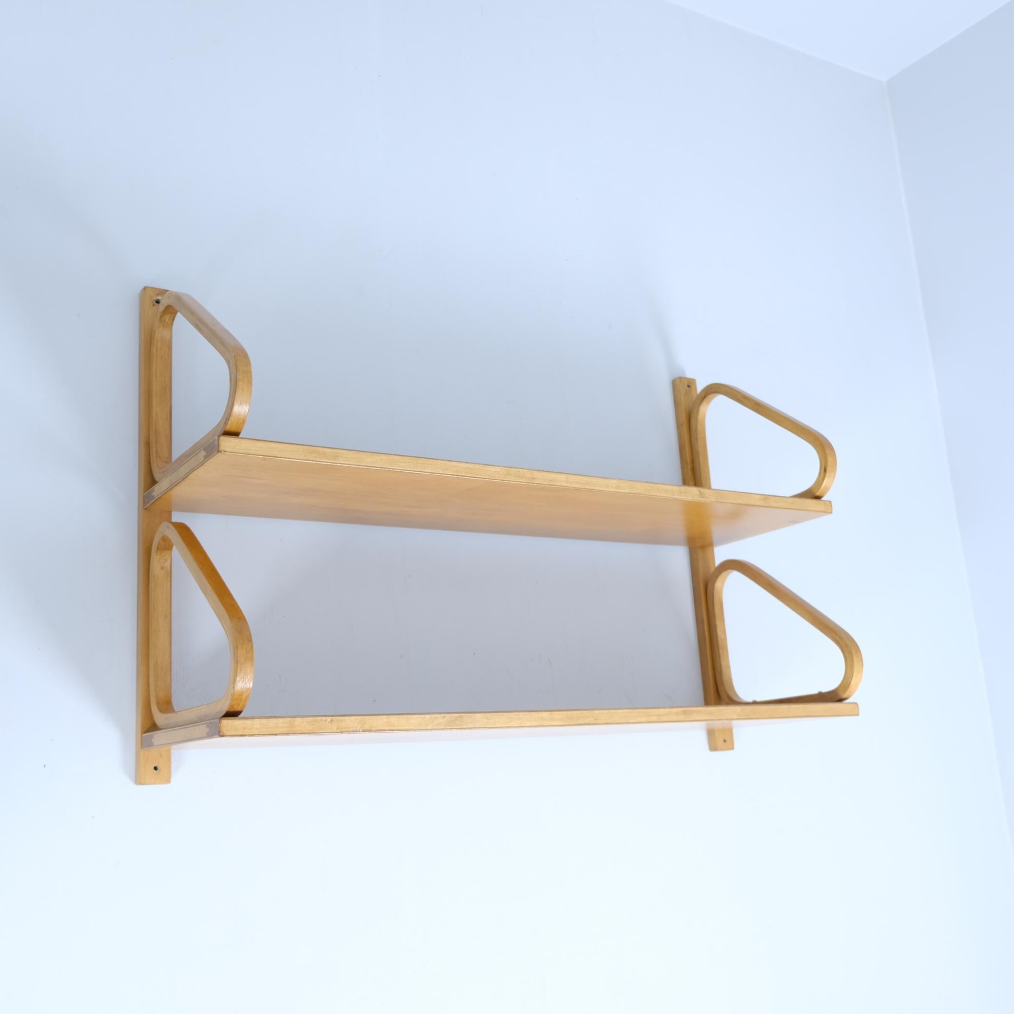 La icónica estantería minimalista de Alvar Aalto en doble piso. Gracias a la barra trasera, la estantería es más fácil de colgar con cuatro tornillos en lugar de ocho.
La estantería es anterior a mediados de la década de 1950 y está hecha con