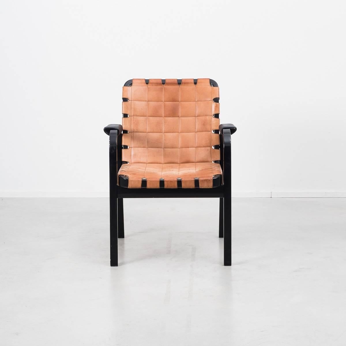 Aalto designed this Classic armchair in 1947 and it remains a sought-after example of his uniquely functional aesthetic. Produced in 1975 from a solid laminated birch frame which supports the quilted tan leather webbing. This webbing forms a durable