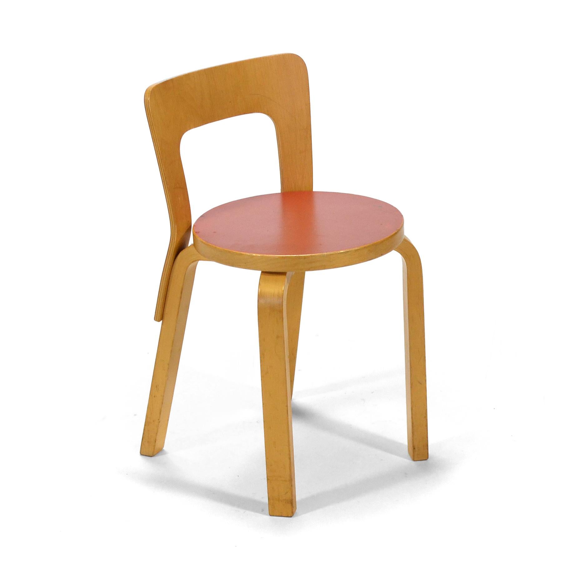 A diminutive chair perfect for children, the 65 chair is a Classic Aalto design with his signature bentwood legs, round seat with red top and plywood back. This vintage example has a beautiful patina from age and use.