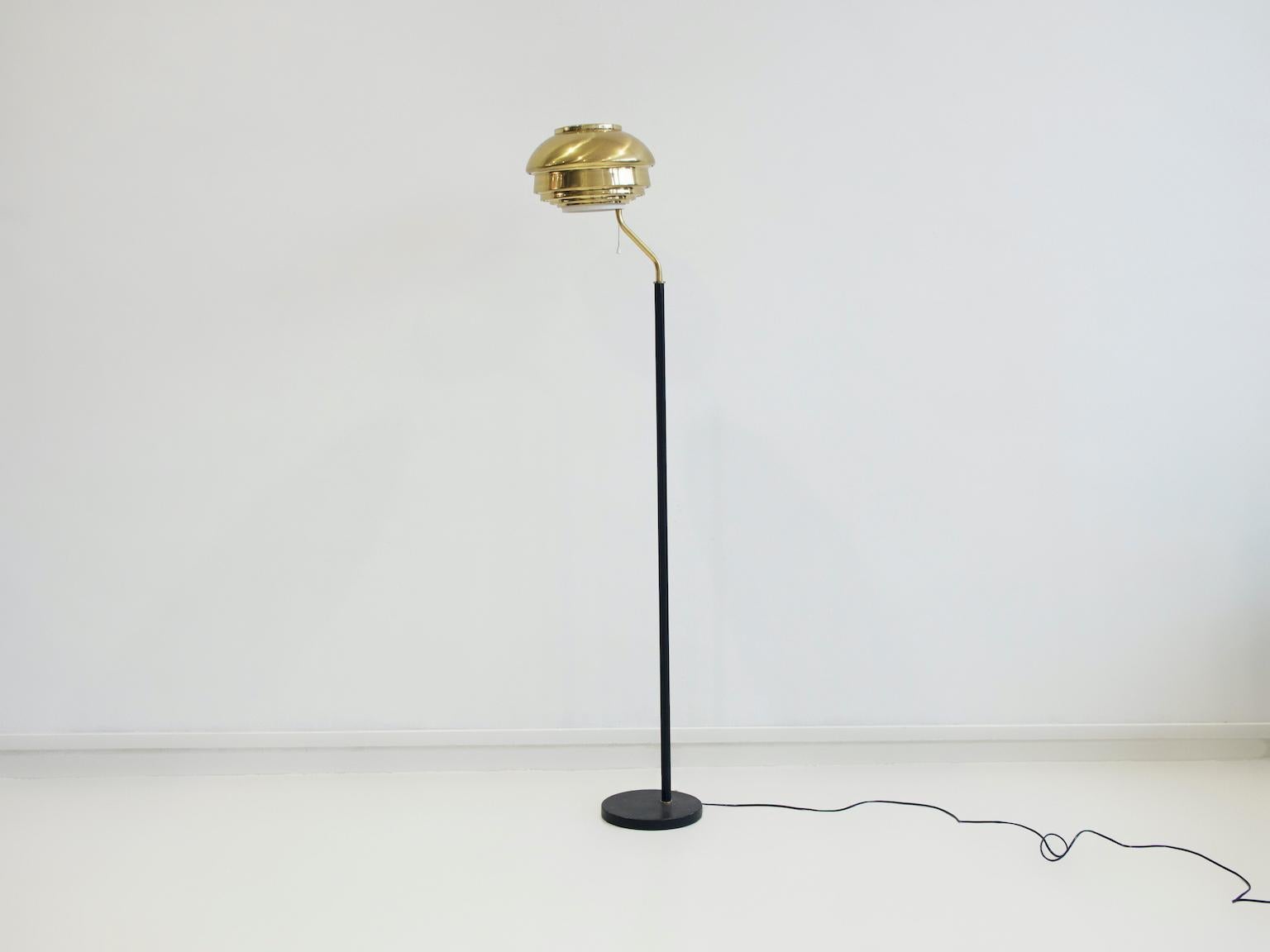 The A808 lamp was designed by Alvar Aalto in 1955 for the National Pensions Institute of Helsinki. This floor lamp has been manufactured by Valaisinpaja Oy, Finland in circa 1970s. The shade is made of layered brass strips and white painted metal,