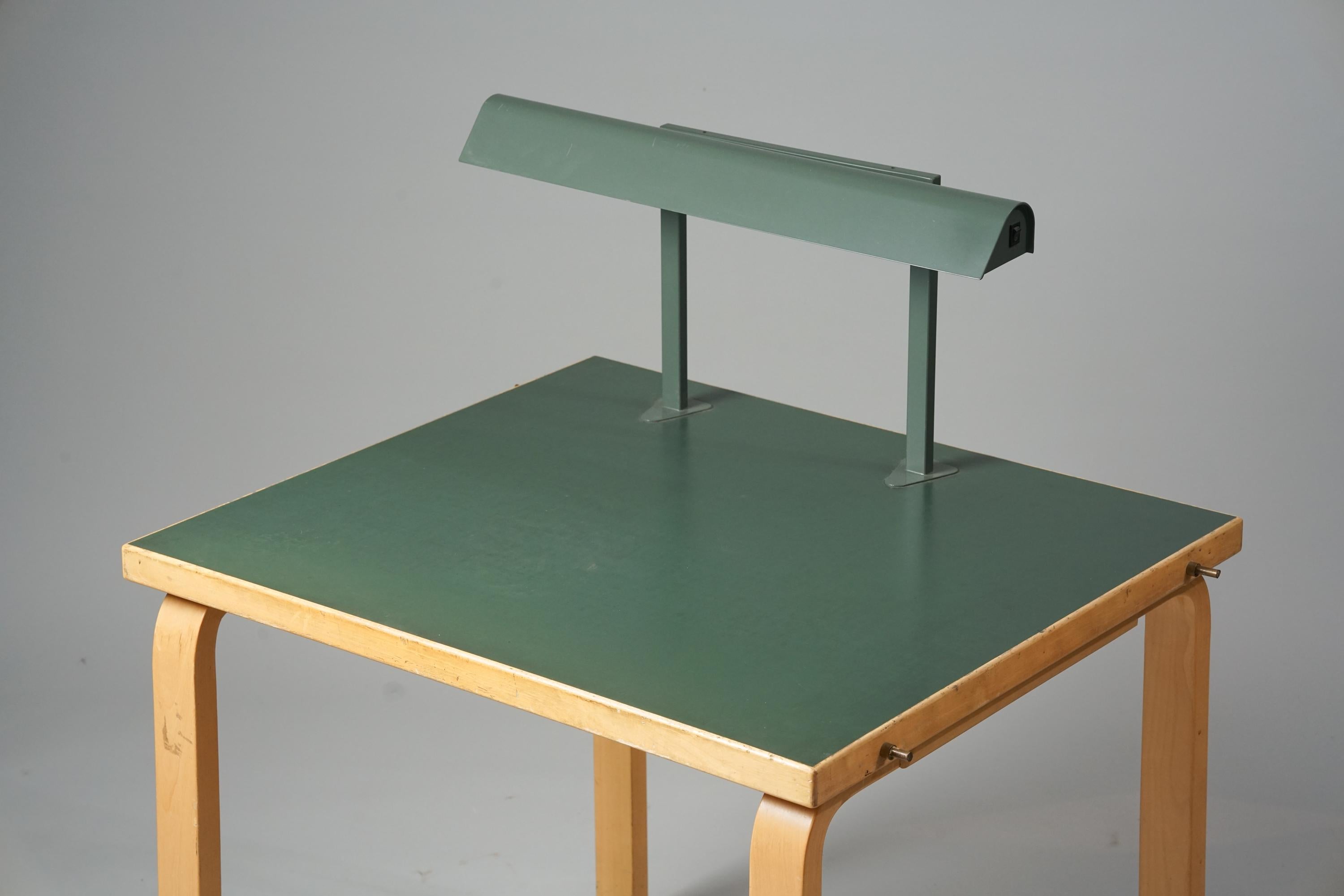 Rare table à écrire, conçue par Alvar Aalto, années 1960. Bouleau avec plateau en linoléum. Modifié plus tard avec la lampe de lecture. La table d'écriture provient de l'université technique d'Otaniemi. Documenté. Bon état vintage, patine mineure