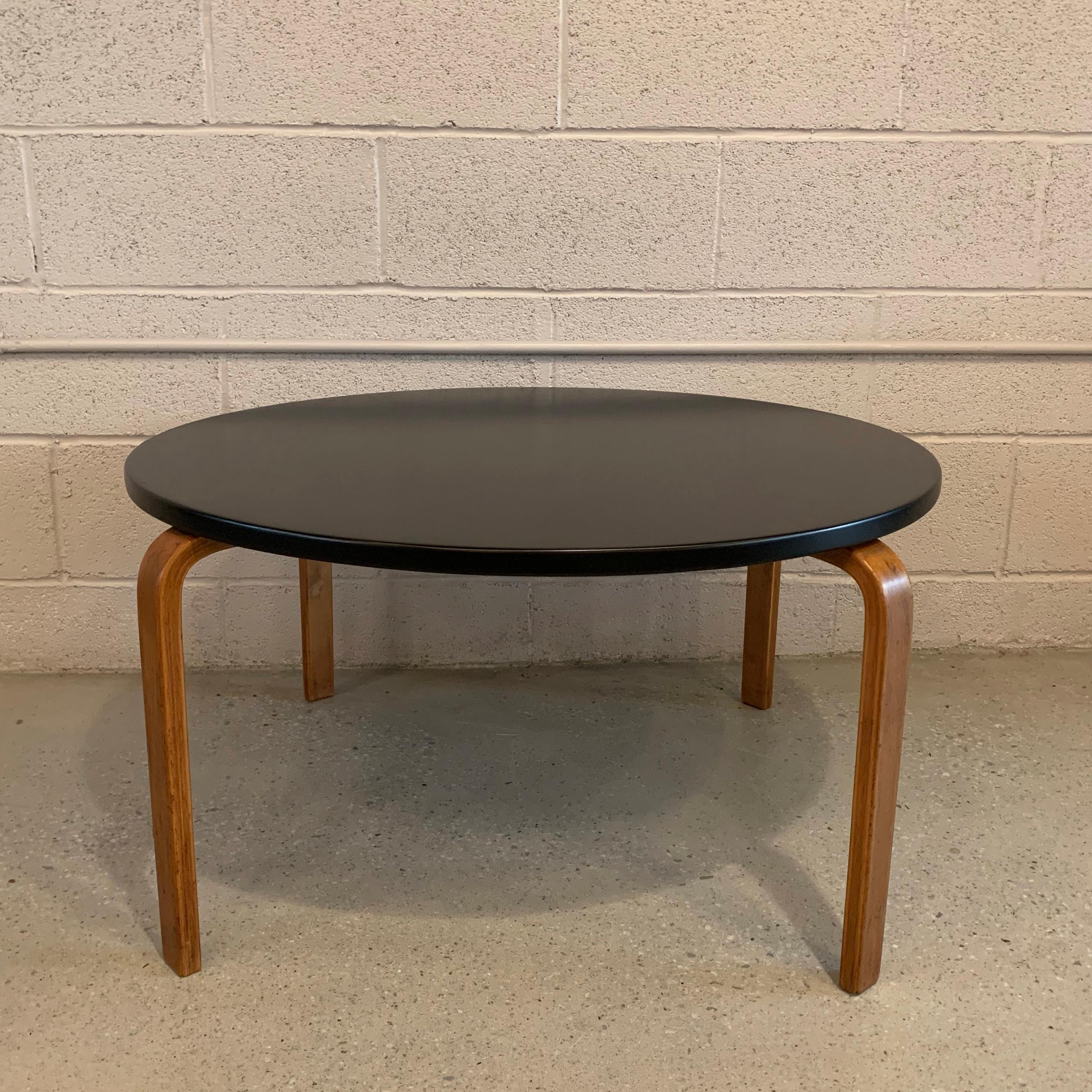 Round, bent brich ply coffee table by Alvar Aalto for Artek features a black lacquered top with natural legs.