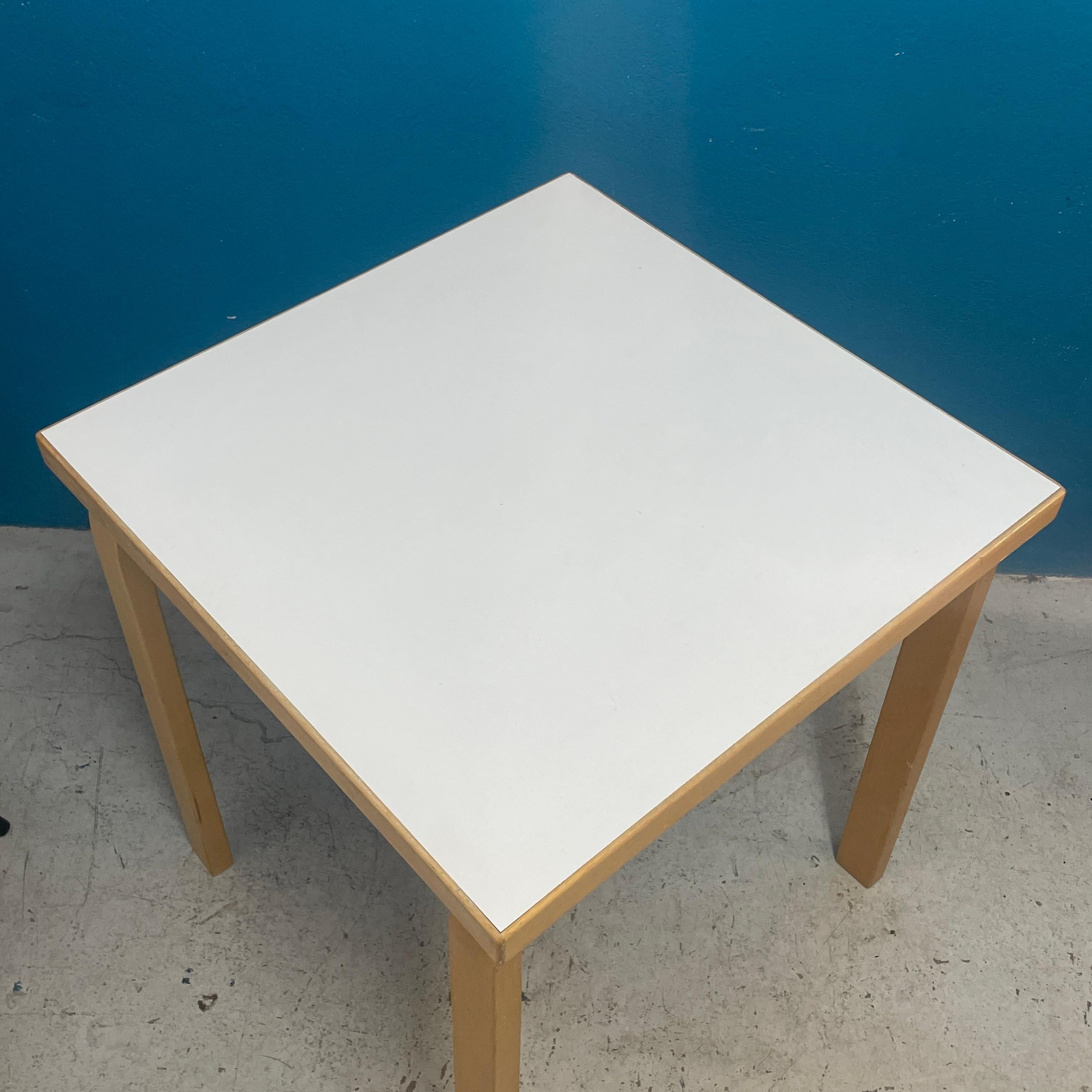 Small Dining Table / Side Table by Alvar Aalto. Timeless design from 1935. Iconic L-Leg construction what Alvar Aalto is famous for.

- Height: 28.3in / 72cm
- Width and Depth 25.5in / 65cm

Table top is white colored  laminate and legs and other