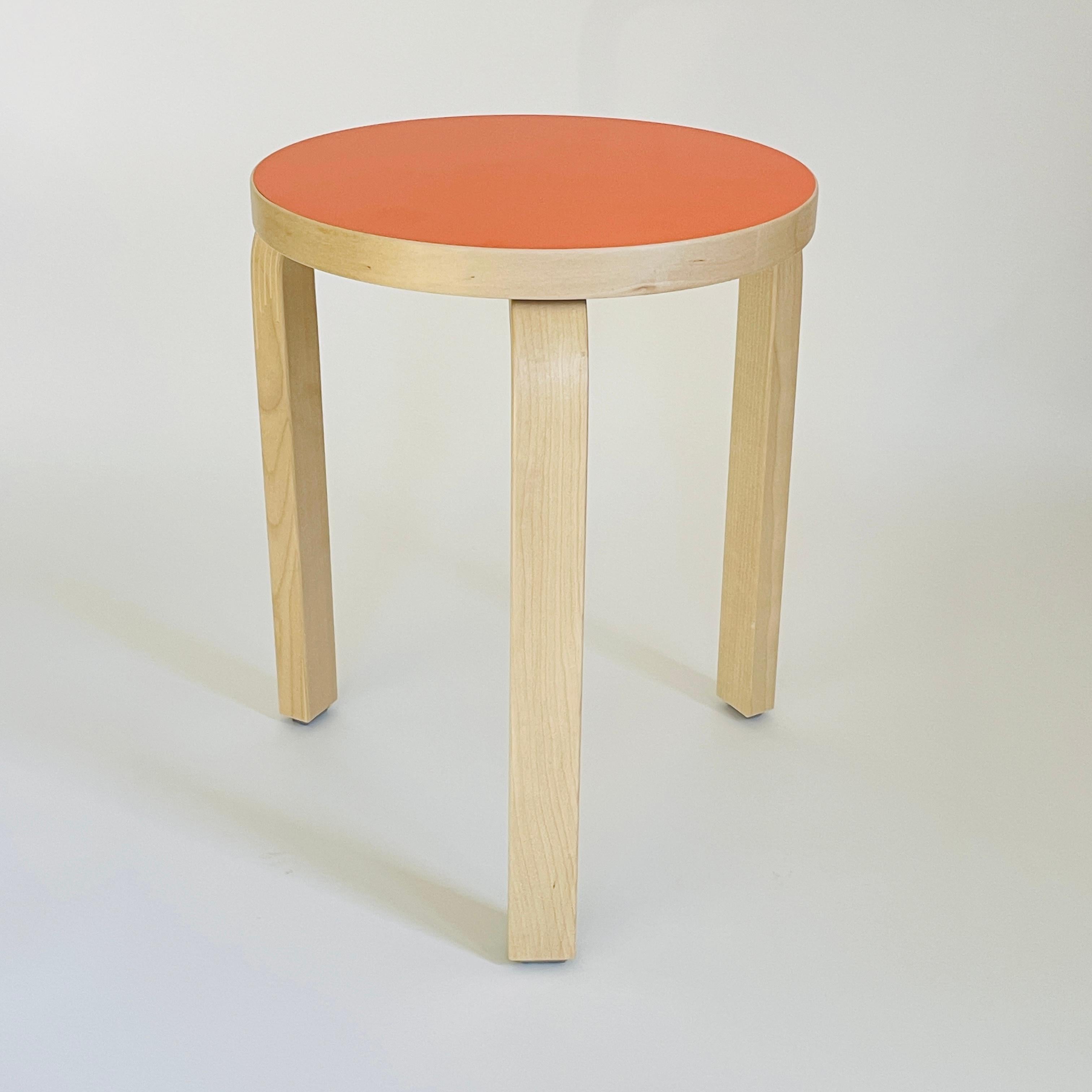 This Aalto stool 60 has a rare color combination, natural birch combined with an orange seat top. This color combination was only produced in 2022.

- Designed By Alvar Aalto
-  Manufactured in 2022, Artek Finland.
- In excellent condition, see