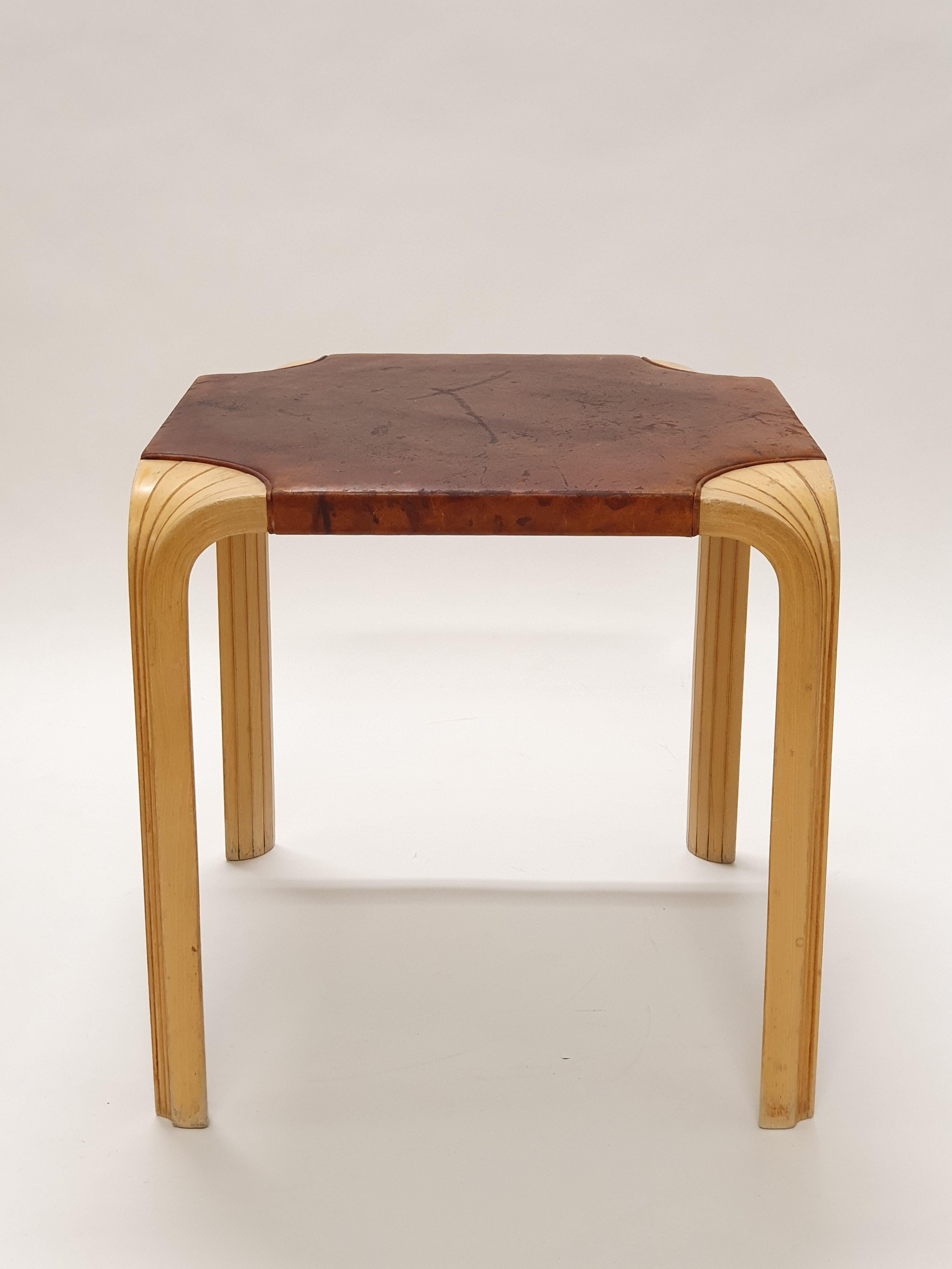 Tabouret Artek X601, design de Alvar Aalto. Bouleau avec cuir d'origine non traité, pieds en éventail, merveilleuse patine du temps. En bon état pour son âge. 

Le tabouret Artek X601, conçu par Alvar Aalto en 1954, est un exemple classique de son