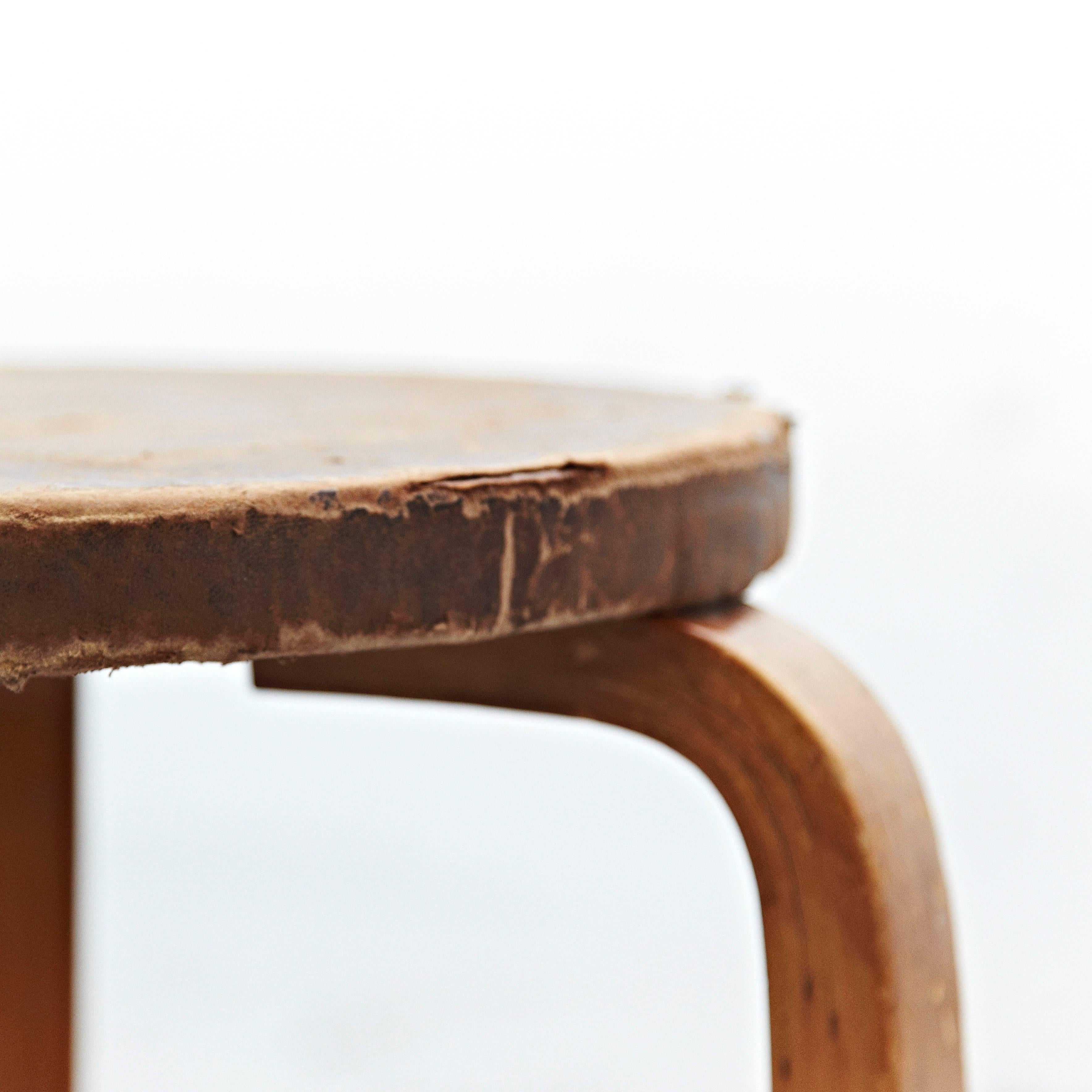 Stool designed by Alvar Aalto, circa 1960.
Manufactured by Artek, (Finland)
Leather top, wood legs and structure.

In great original condition, with minor wear consistent with age and use in the structure some broken leather top, preserving a