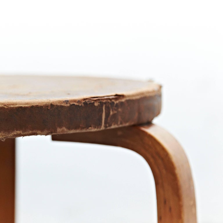 Stool designed by Alvar Aalto, circa 1960.
Manufactured by Artek, (Finland)
Leather top, wood legs and structure.

In great original condition, with minor wear consistent with age and use in the structure some broken leather top, preserving a