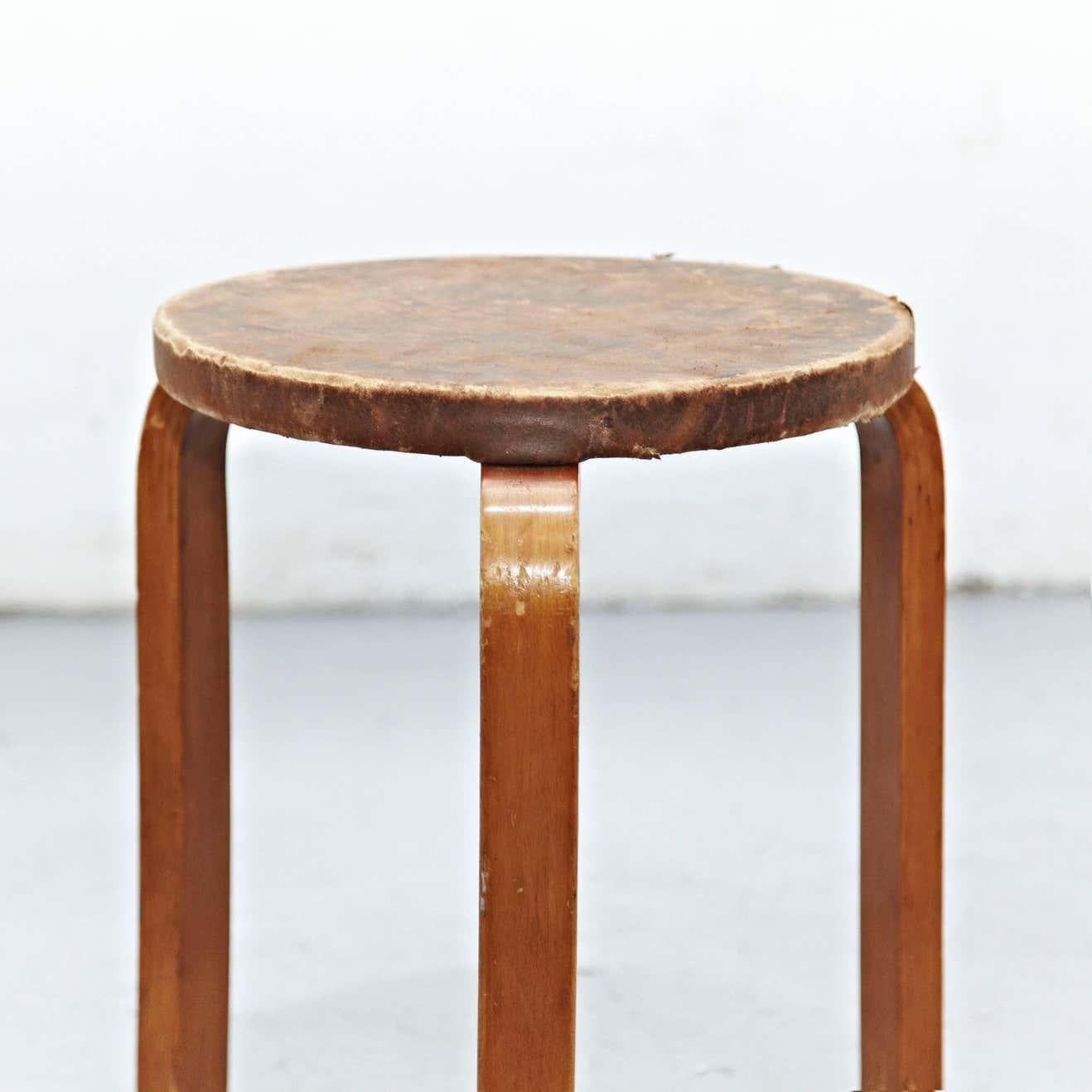 Stool designed by Alvar Aalto, circa 1960.
Manufactured by Artek, (Finland)
Leather top, wood legs and structure.

In great original condition, with minor wear consistent with age and use in the structure some broken leather top, preserving a