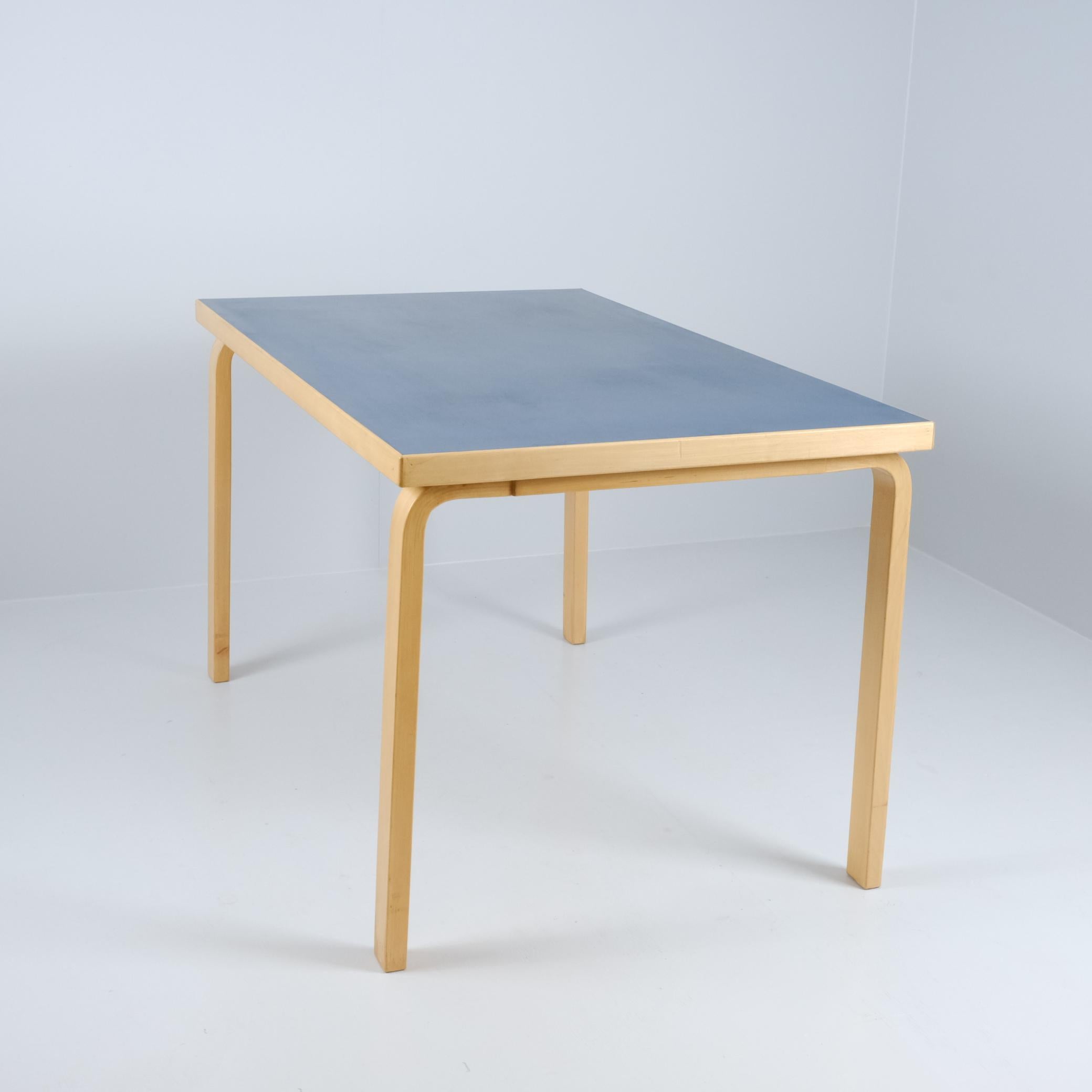 A classic L-leg table designed by Alvar Aalto, manufactured by Huonekalu- ja Rakennustehdas Oy and retailed by Artek in Finland. This piece exhibits a beautiful vintage patina, with the original blue linoleum top showing gentle signs of age—minor