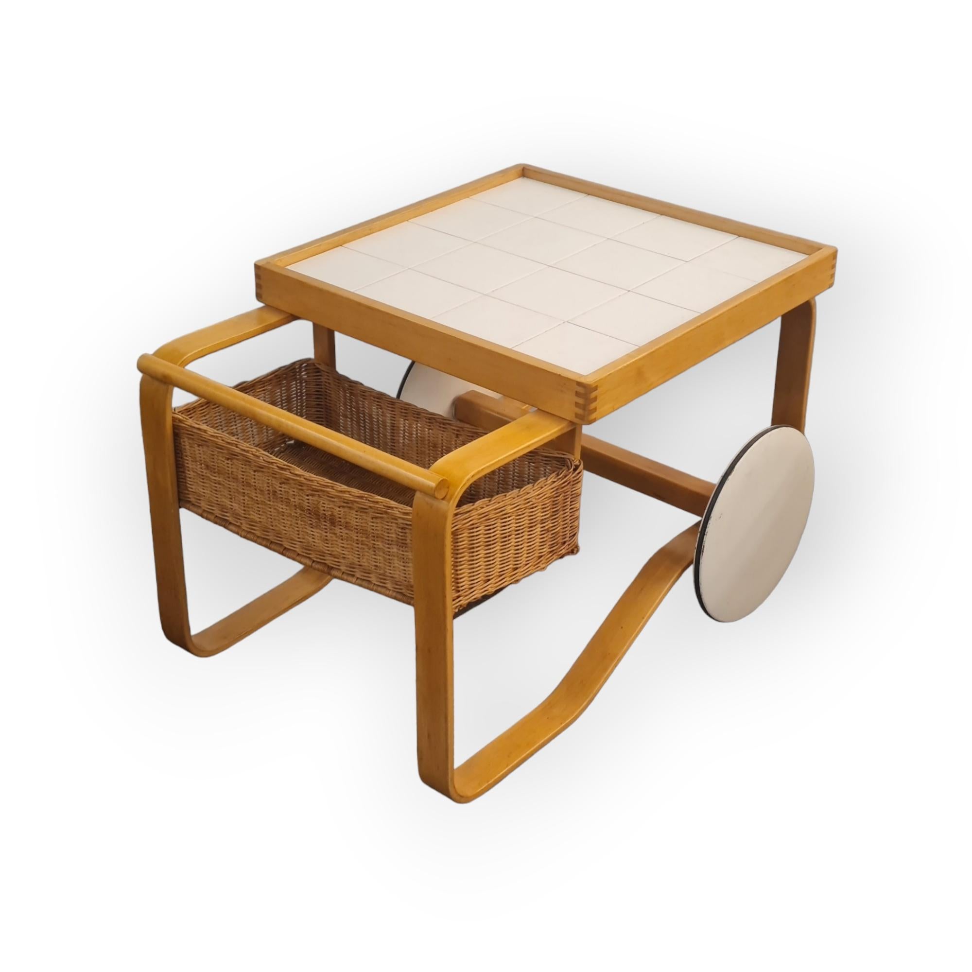 One of the most iconic and sought after pieces designed by Alvar Aalto. This traditional, elegant and pragmatic tea cart is made in the style of Scandinavian modern design. The trolley features ceramic tiles, and a rattan basket which makes it