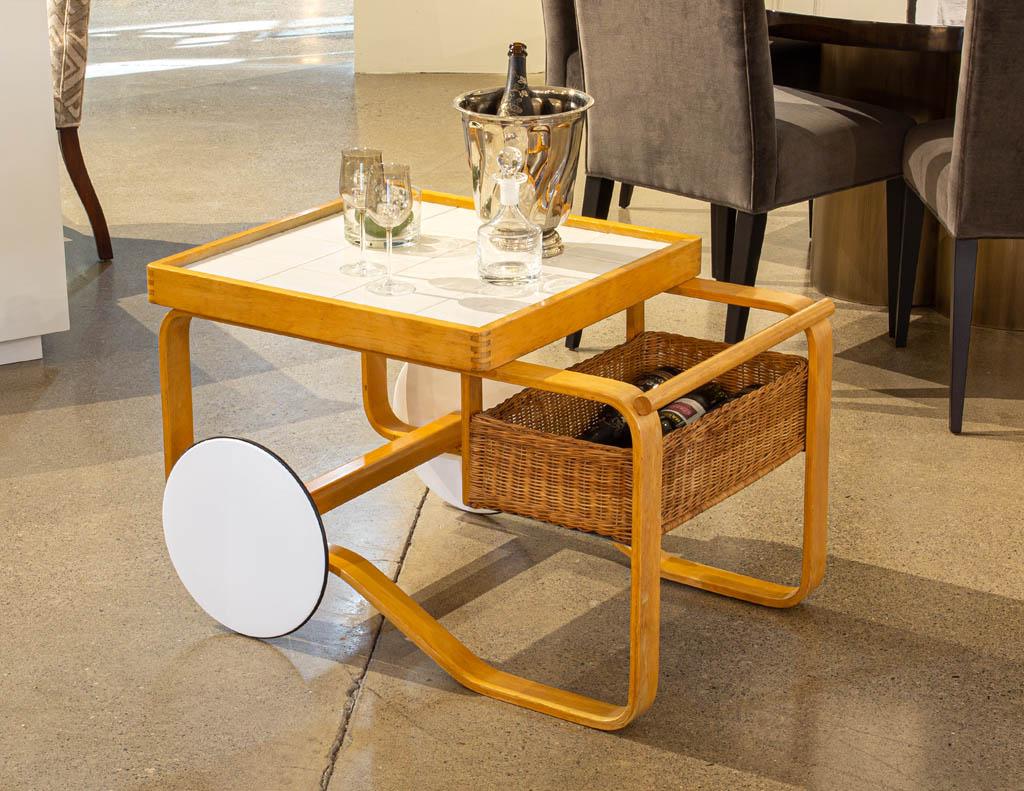 Alvar Aalto tea trolley 900 Modern bar cart. Iconic Scandinavian modern design by Alvar Aalto. The trolley features ceramic tiles, and a rattan basket which makes it perfect for serving. This iconic piece was first displayed at the World Exhibition