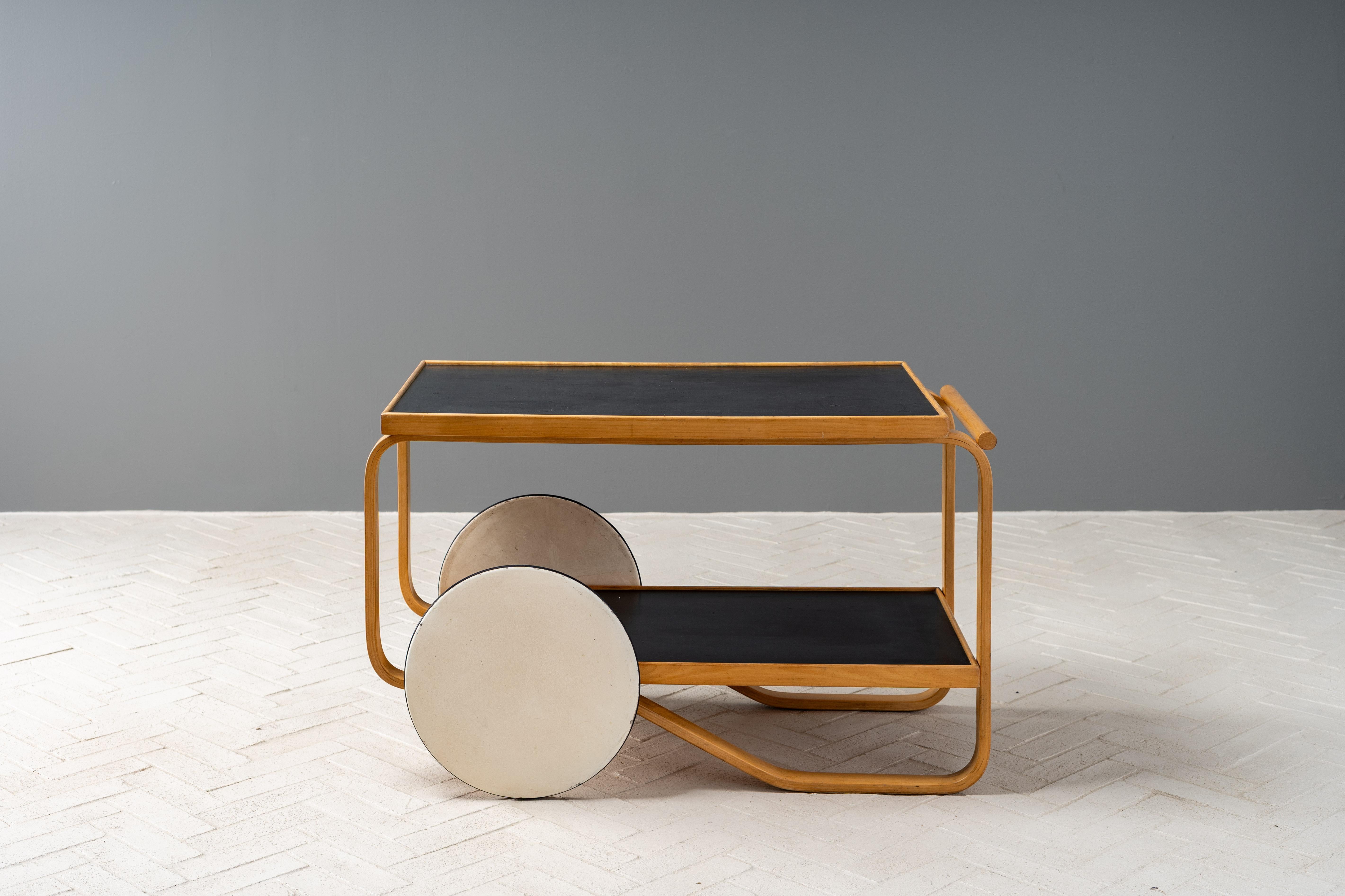 Finland, ca. 1950s. A rare and early Model 901 tea trolley or bar cart by Alvar Aalto for Artek. Features a solid birch frame with black linoleum shelving and large white lacquered wooden wheels - fitted with rubber treads. Originally debuted at the
