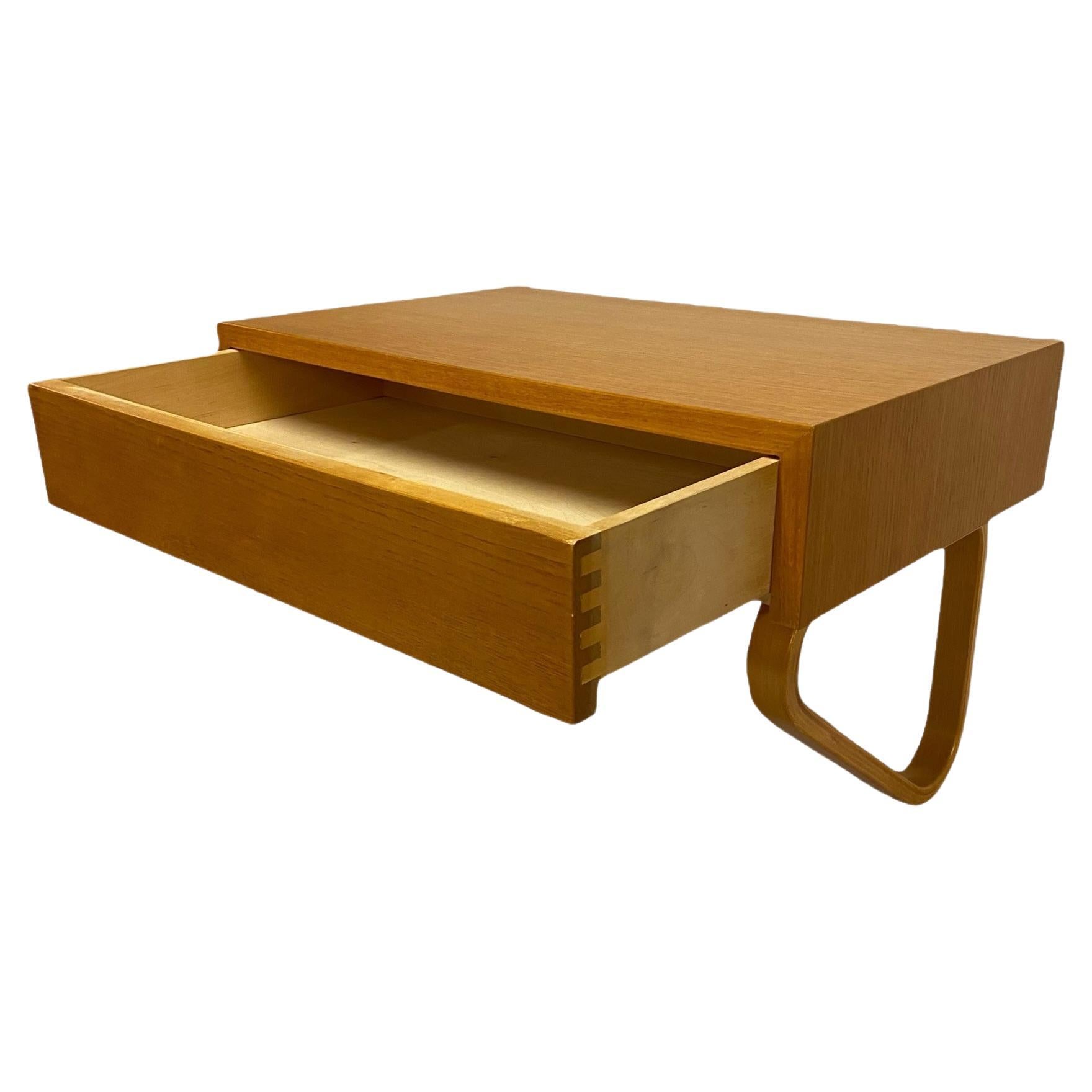 This type wall shelf by Alvar Aalto is very sought after. There is just not enough of them to go around.

As one can see from the archive picture the shelf can be joined with a mirror and a stool to have a nice set for the hallway for example (