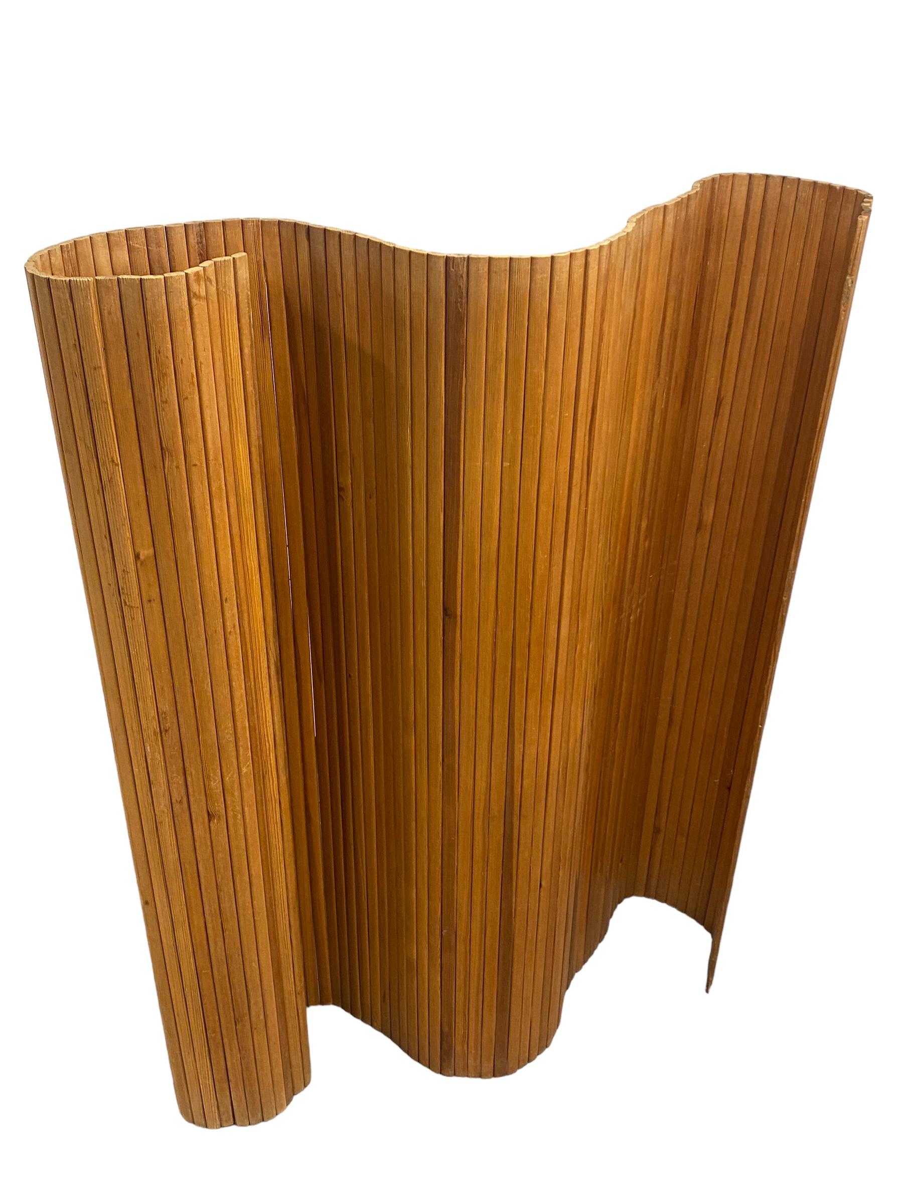 Le mur / séparateur de pièces à lattes 100 d'Alvar Aalto est un élément d'intérieur dynamique assemblé à partir d'étroites lattes verticales en pin. Il peut être enroulé et ouvert en position droite ou dans de nombreuses positions incurvées. D'une