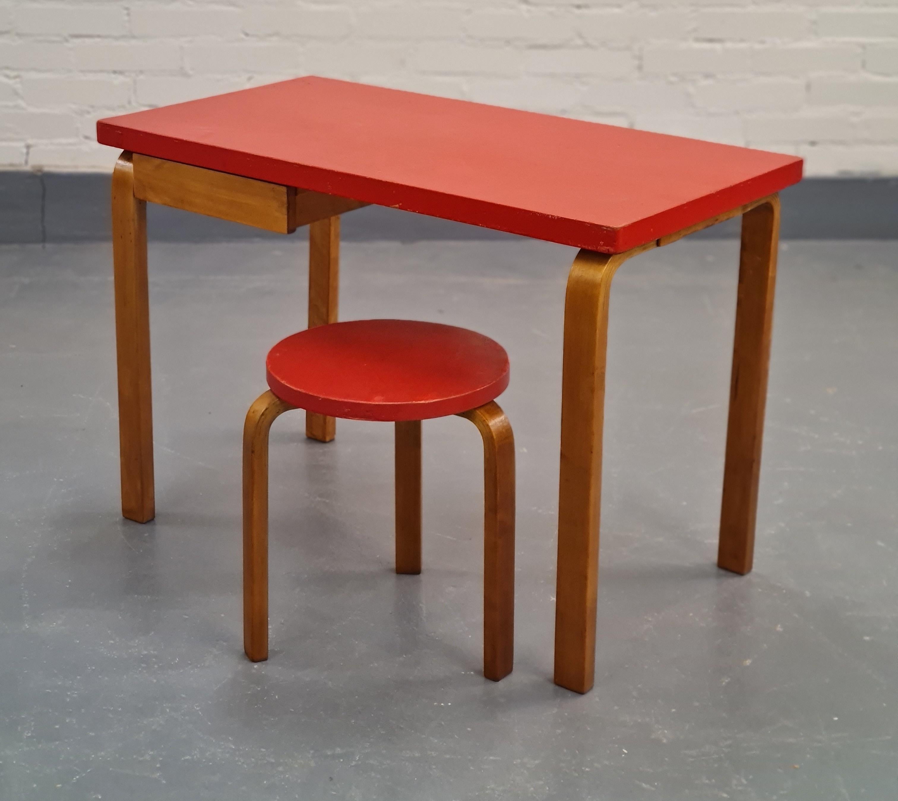 An iconic Aalto set including the model K81 writing table and the model 60 stool, both in a beautiful red coat of paint and an astonishing patina. Both pieces have maintained a great condition and the legs have developed a matching dark, coffee