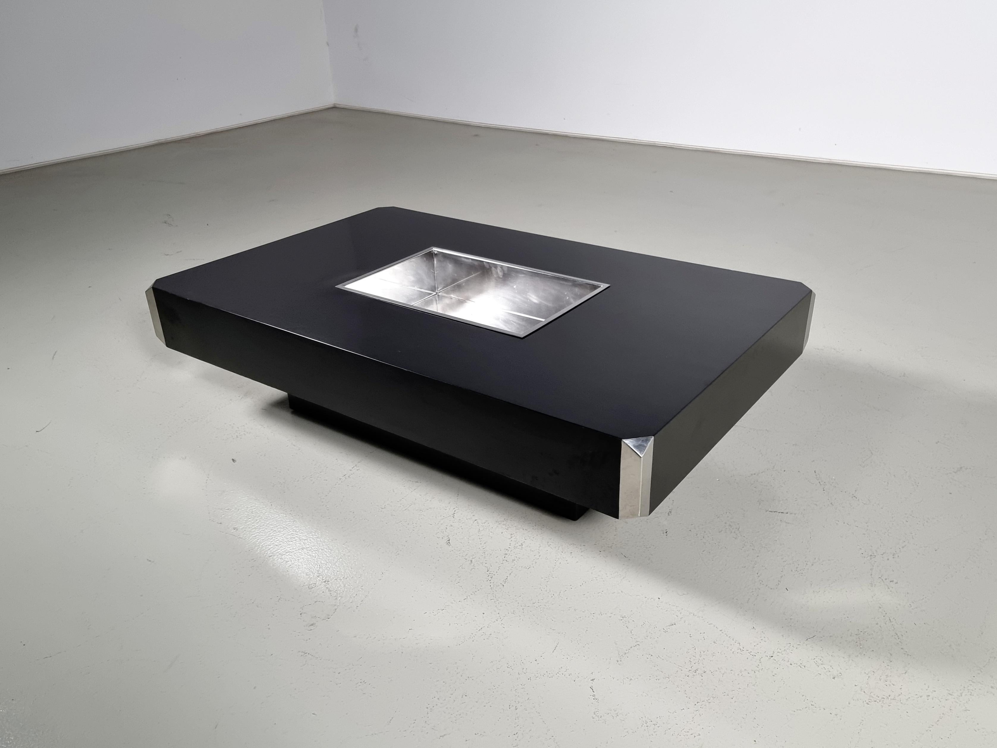 Coffee table Willy Rizzo for Mario Sabot from the 1970s

Made from gorgeous chrome with a black lacquered wood base.
The recessed base creates the impression that the table is floating and lightens the aesthetic.  One of the distinctive features of