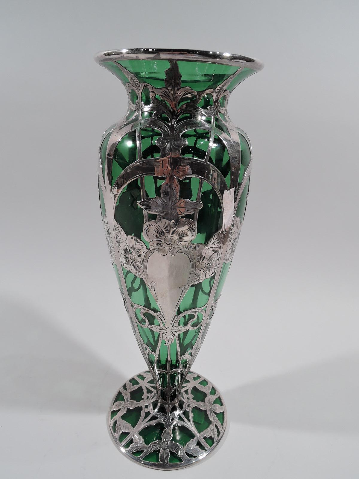 Turn-of-the-century Art Nouveau glass vase with engraved, silver overlay. Made by Alvin in Providence. Curved and tapering sides, short neck with flared rim, and round and slightly raised foot. Structured and vertical overlay in form of arched