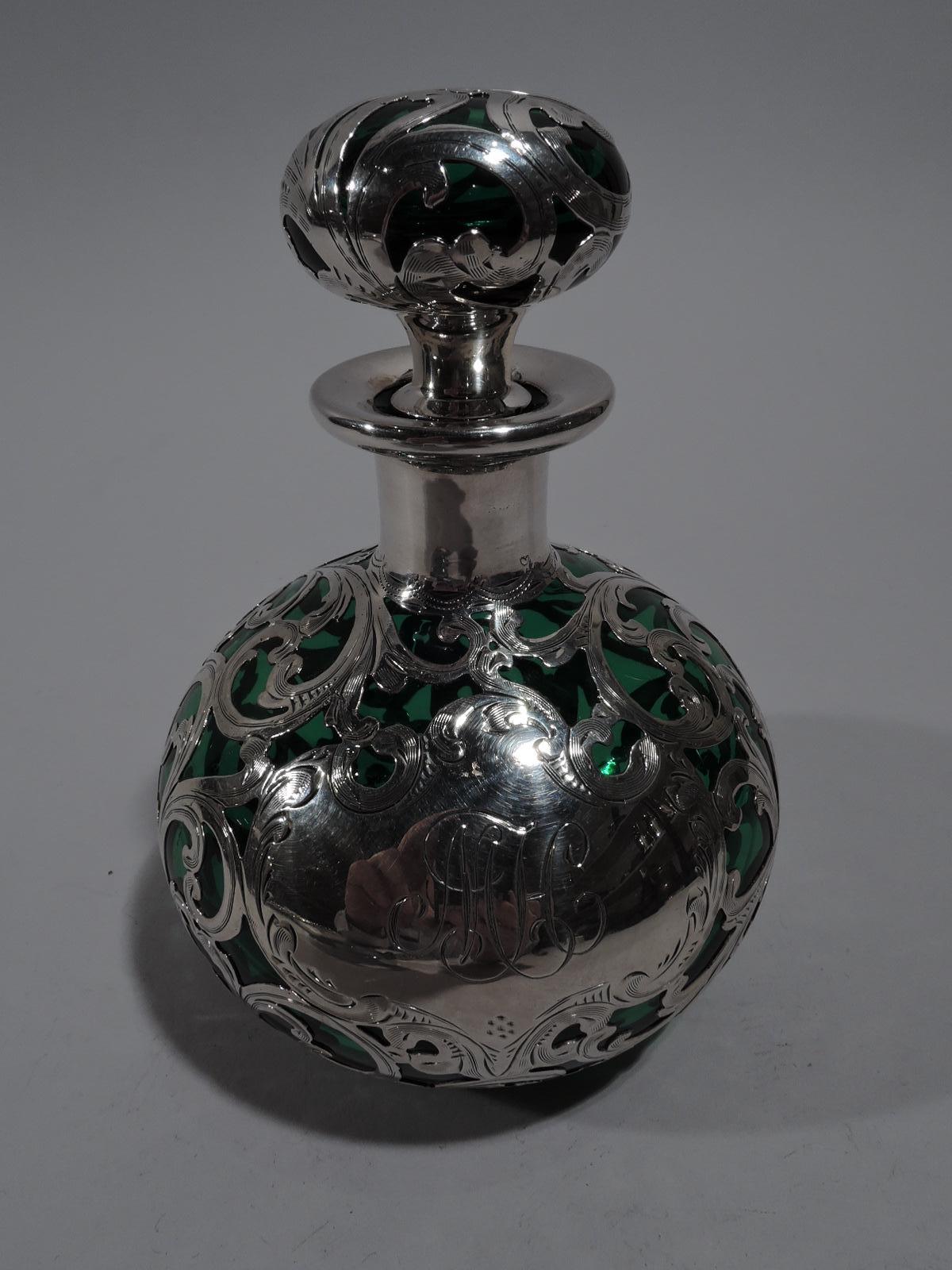 Art Nouveau green glass perfume bottle with silver overlay. Made by Alvin in Providence, circa 1900. Globular with short neck and everted rim. Squat ball finial with short plug Silver overlay in form of dense and interlaced scrollwork. Armorial