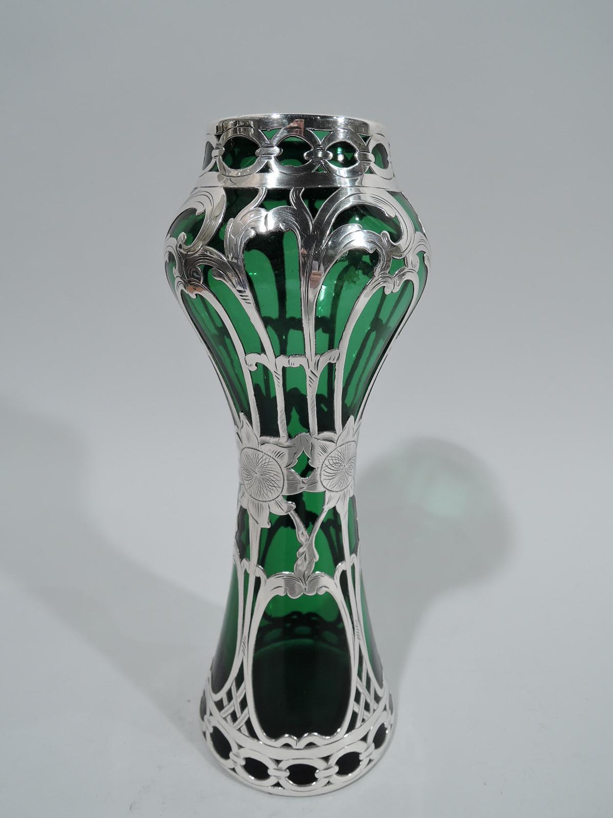 Turn-of-the-century Art Nouveau glass vase with engraved silver overlay. Waisted center with curved shoulder and conical base. Vertical overlay with scrolling tendrils and sunflower-head girdle. Top and bottom have guilloche borders. Glass is green.