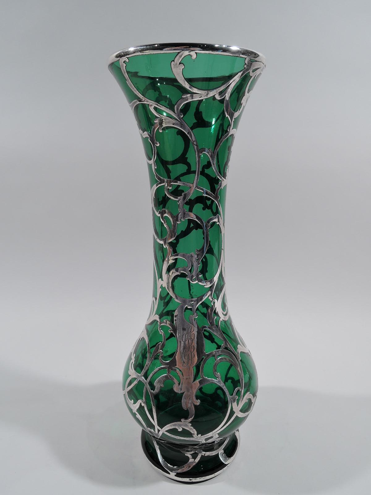 Turn-of-the-century Art Nouveau glass vase with engraved silver overlay. Made by Alvin in Providence. Flared mouth, cylindrical neck, gently globular bowl, and inset foot. Fluid and open leafy scroll overlay, and asymmetrical cartouche engraved with